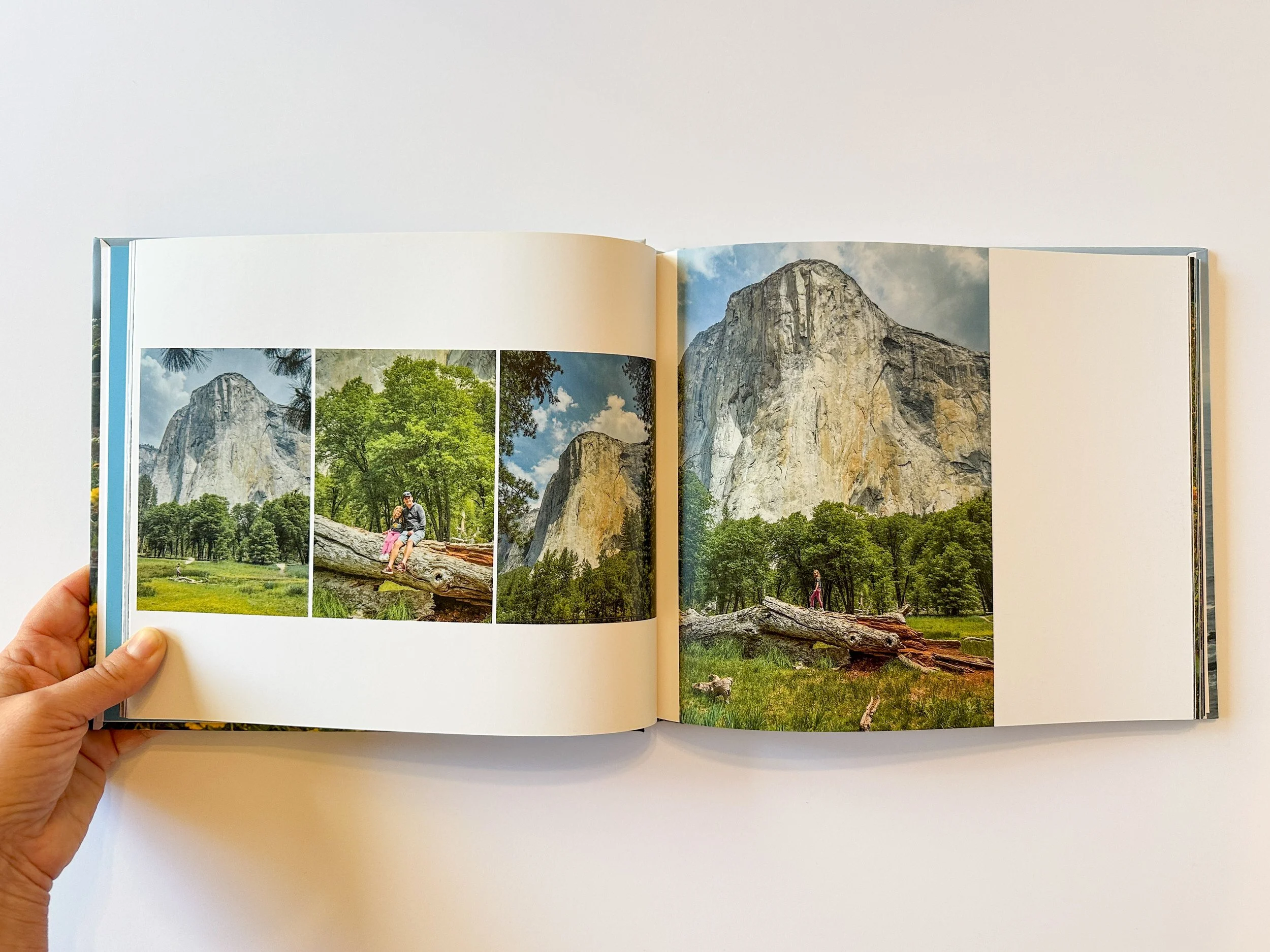 Open photo book showing landscape images of El Capitan in Yosemite with trees and a person sitting on a fallen log.