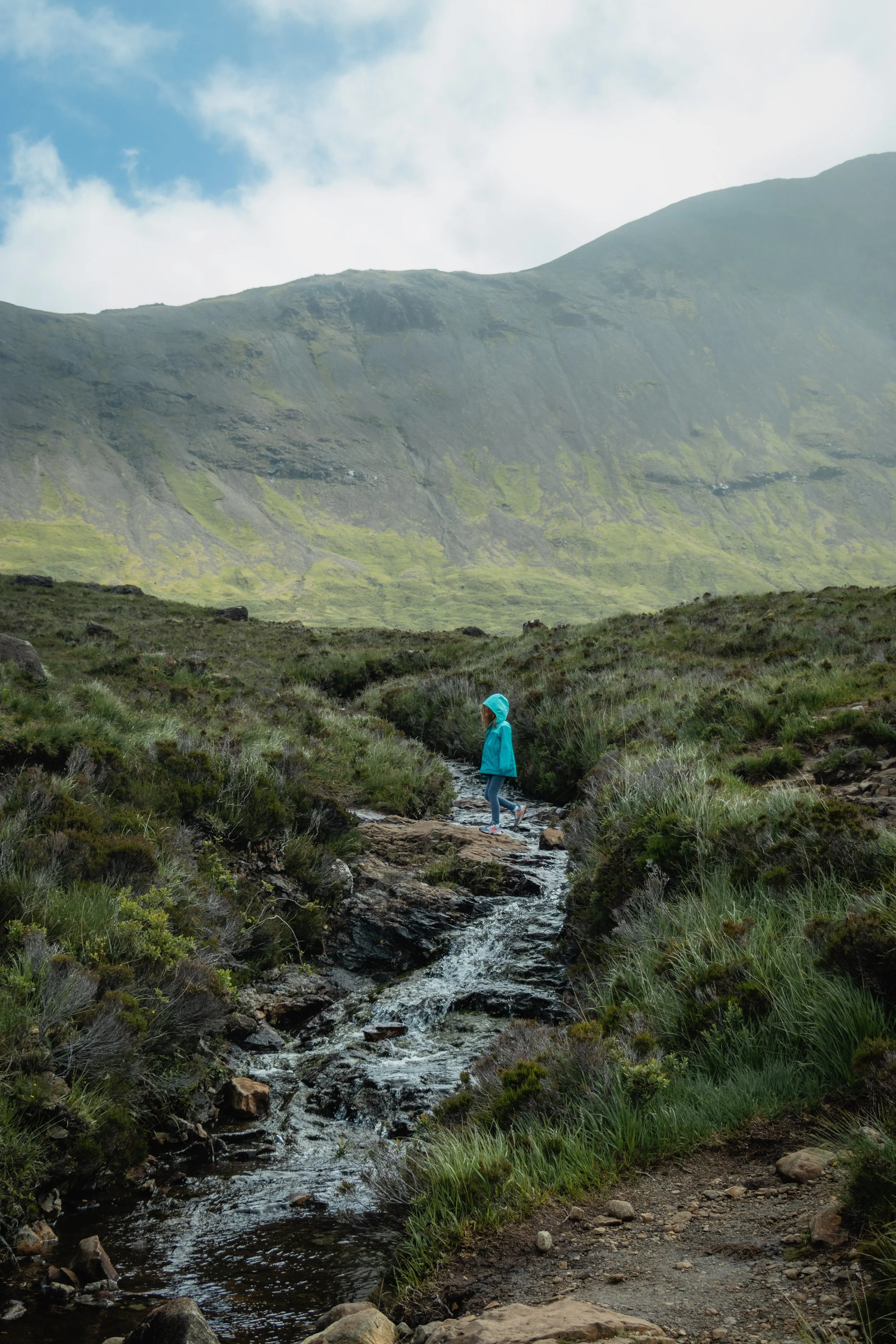 A girl crossing over a river in the Fairy Pools on the Isle of Skye in Scotland