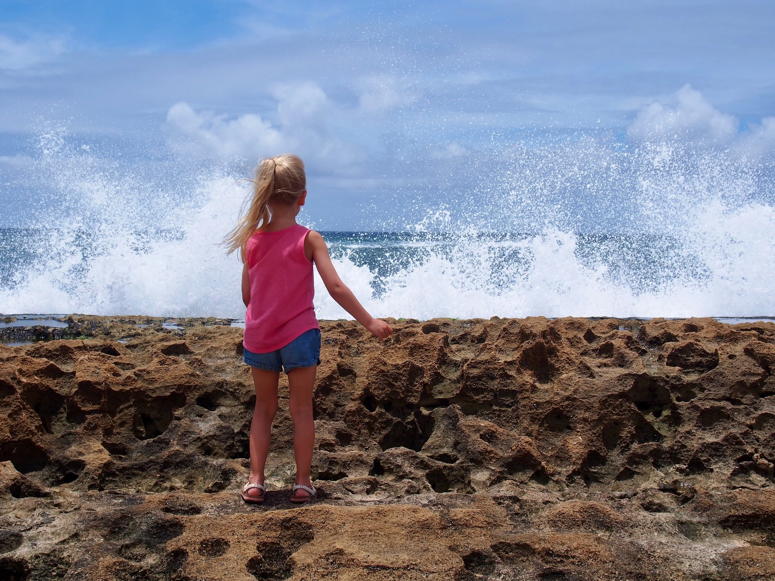 A girl in front of crashing waves on Ho'okipa Beach in Paia, Hawaii