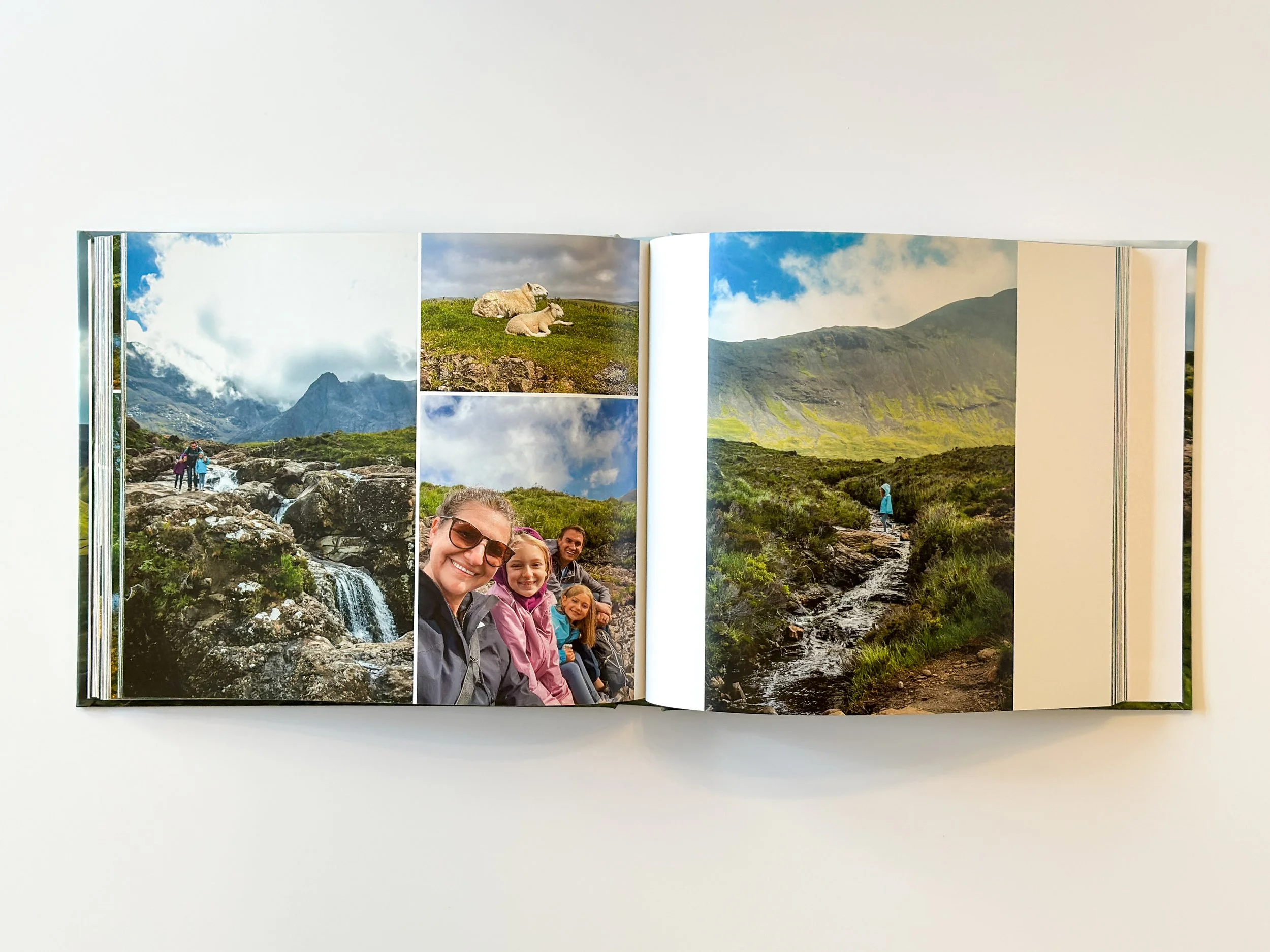 Open photo album containing scenic outdoor photos of mountains, a waterfall, people hiking, and a group of smiling children and adults taking a selfie in a green landscape.