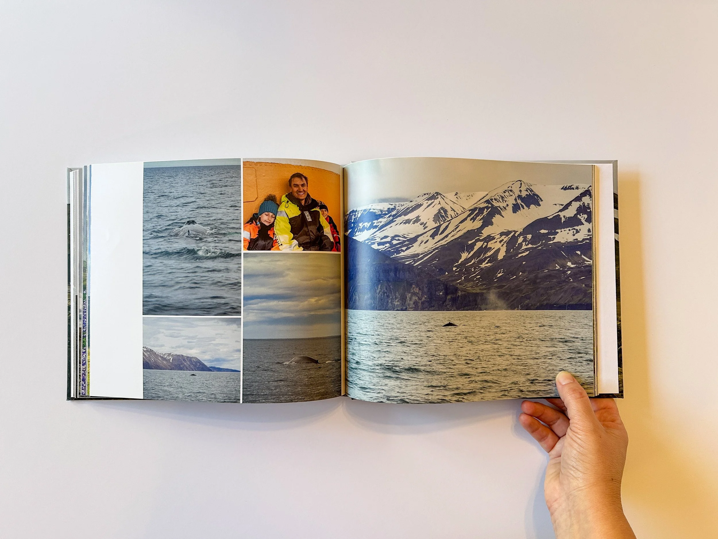 Open photo album with images of whales in the ocean, a smiling woman with children on a boat, and snow-capped mountains.