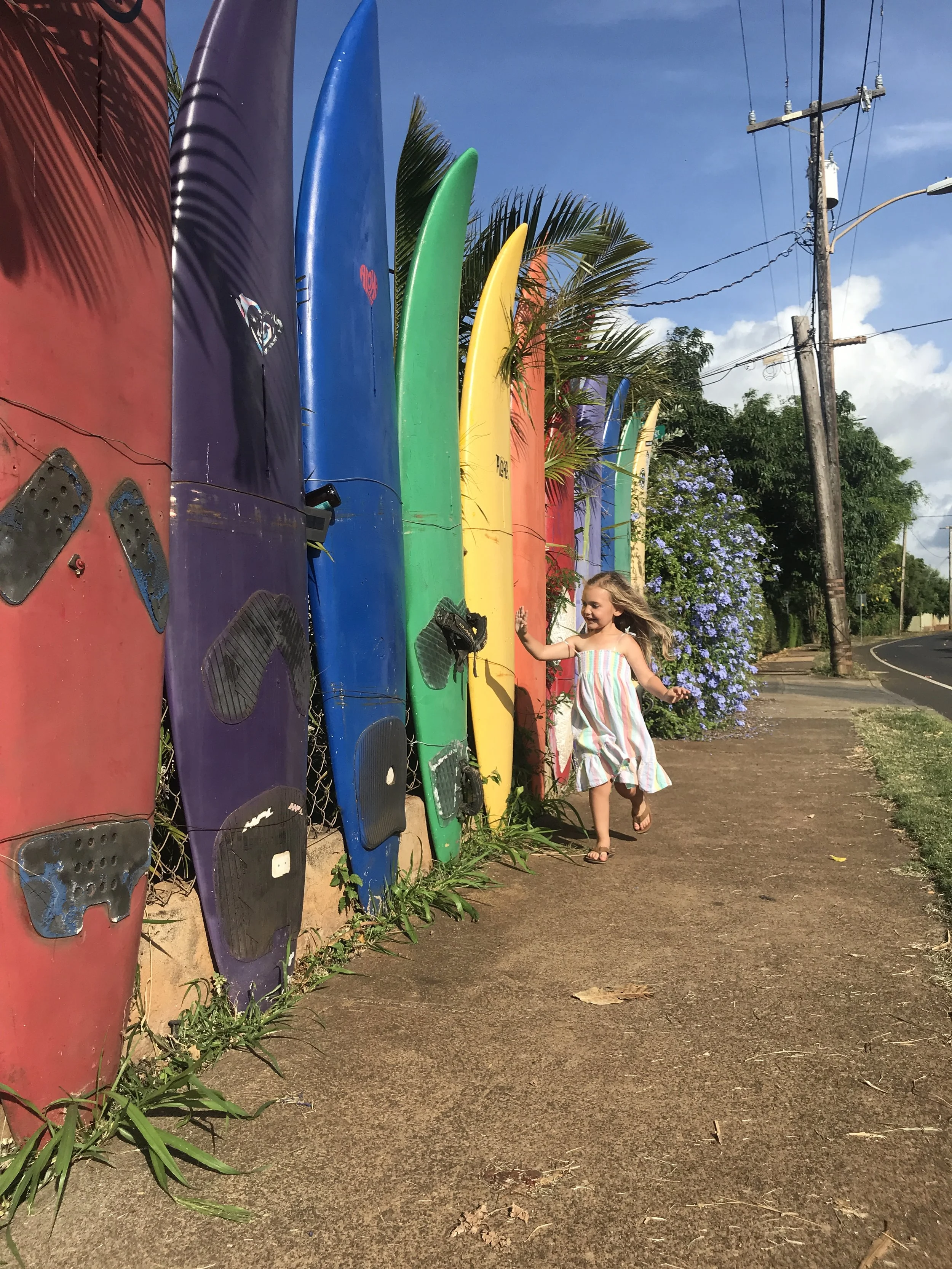 A girl running along colorful surfboards in Paia, Hawaii