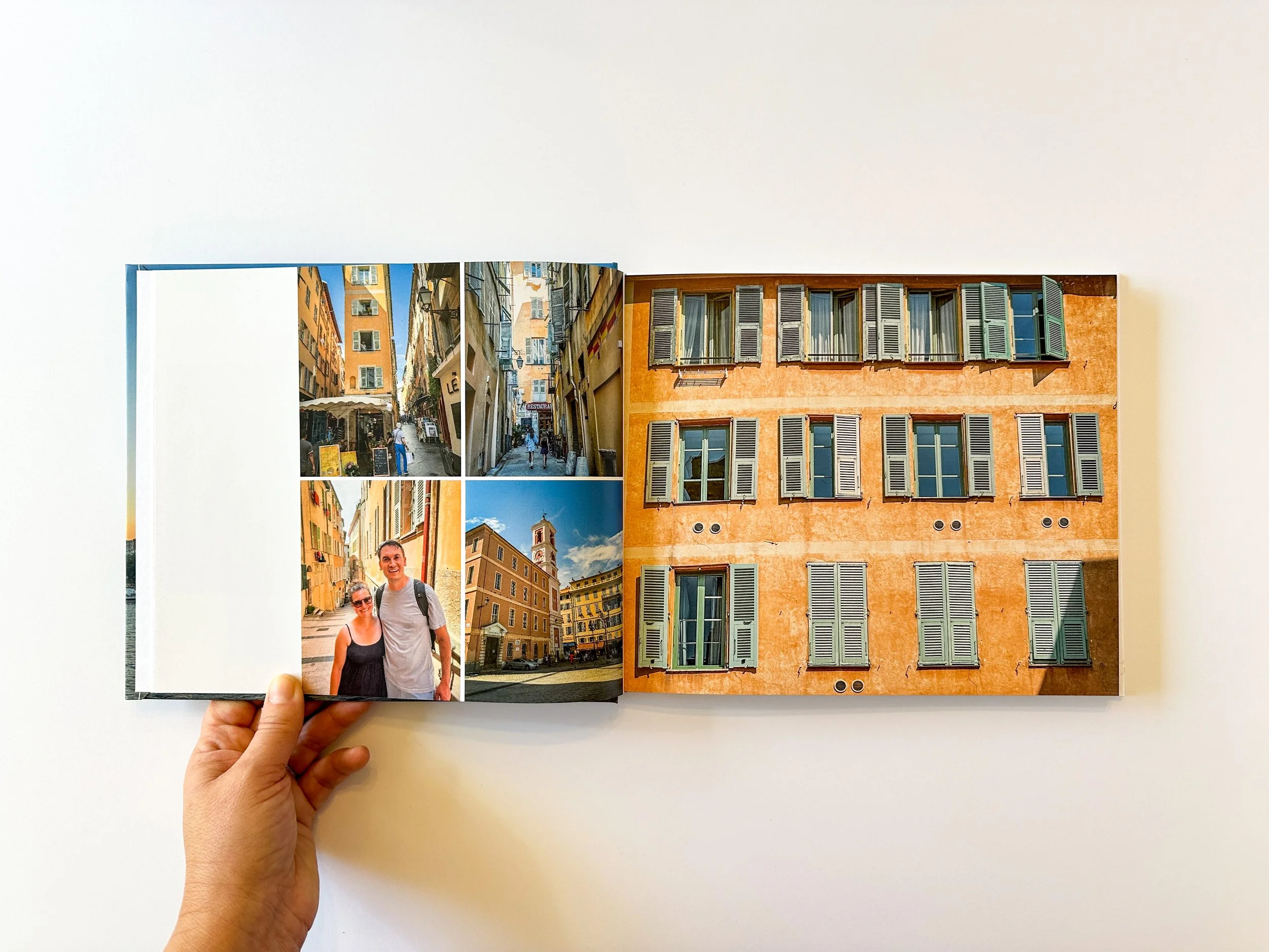 Open travel photo album showing four images of European city streets and a building with windows and shutters.