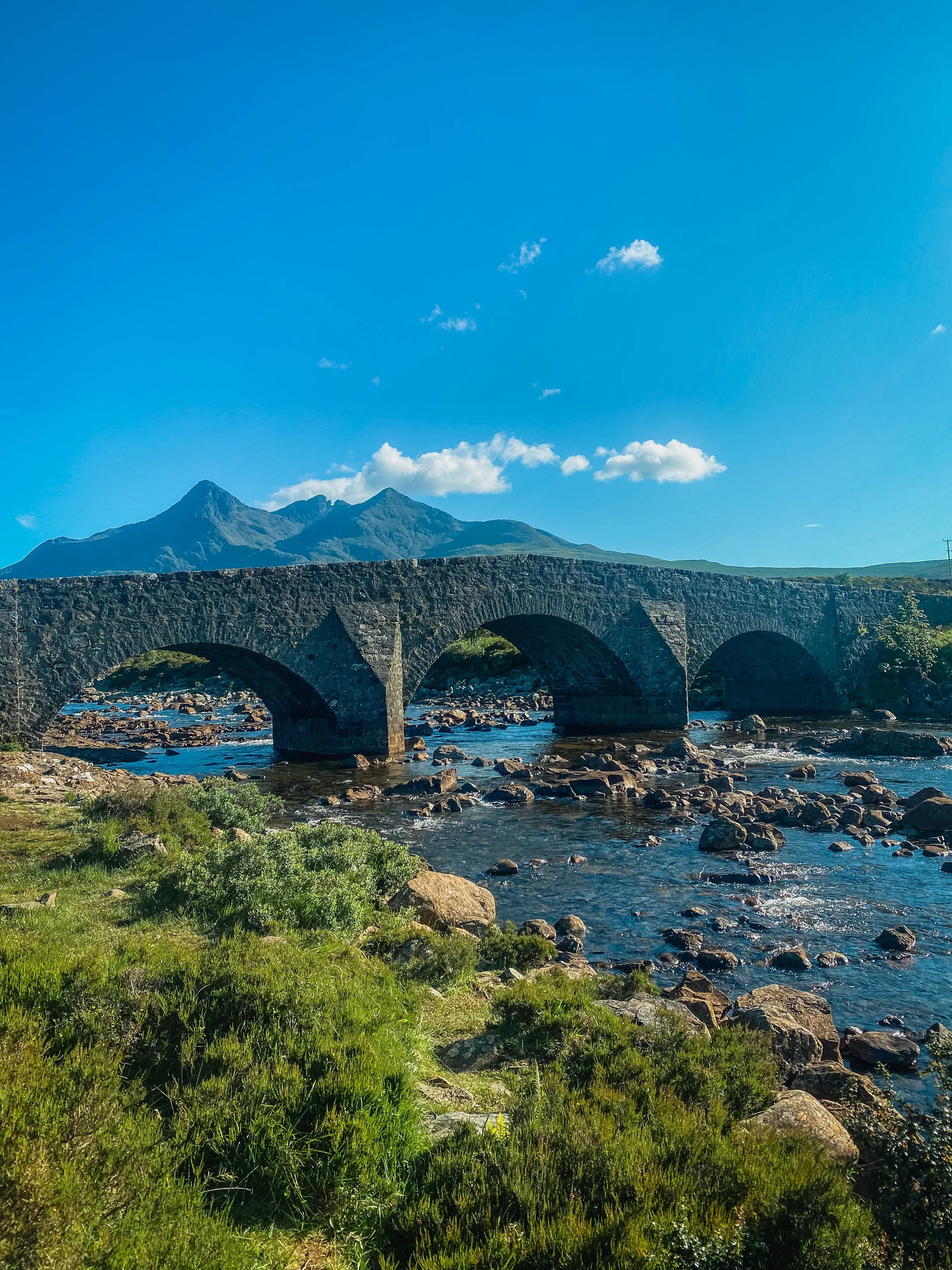 View of the Fairy Bridge with mountains in the background on the Isle of Skye in Scotland.