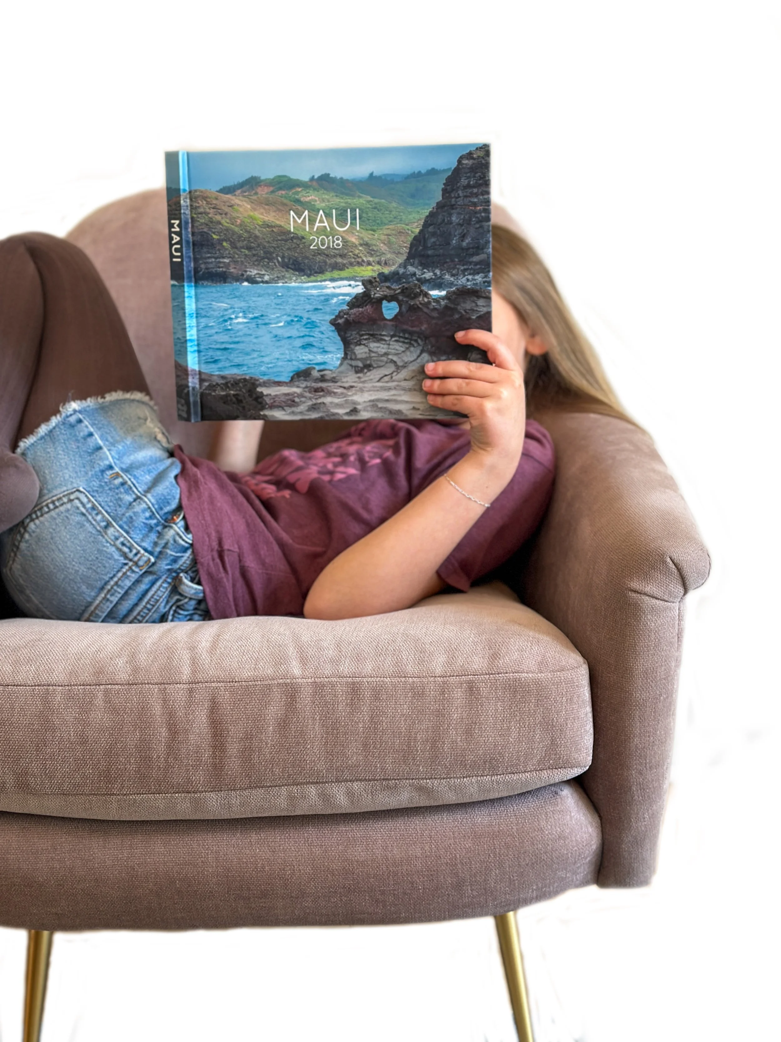 A girl reading a custom photo book from a vacation to Maui made by Forever Bound Studio