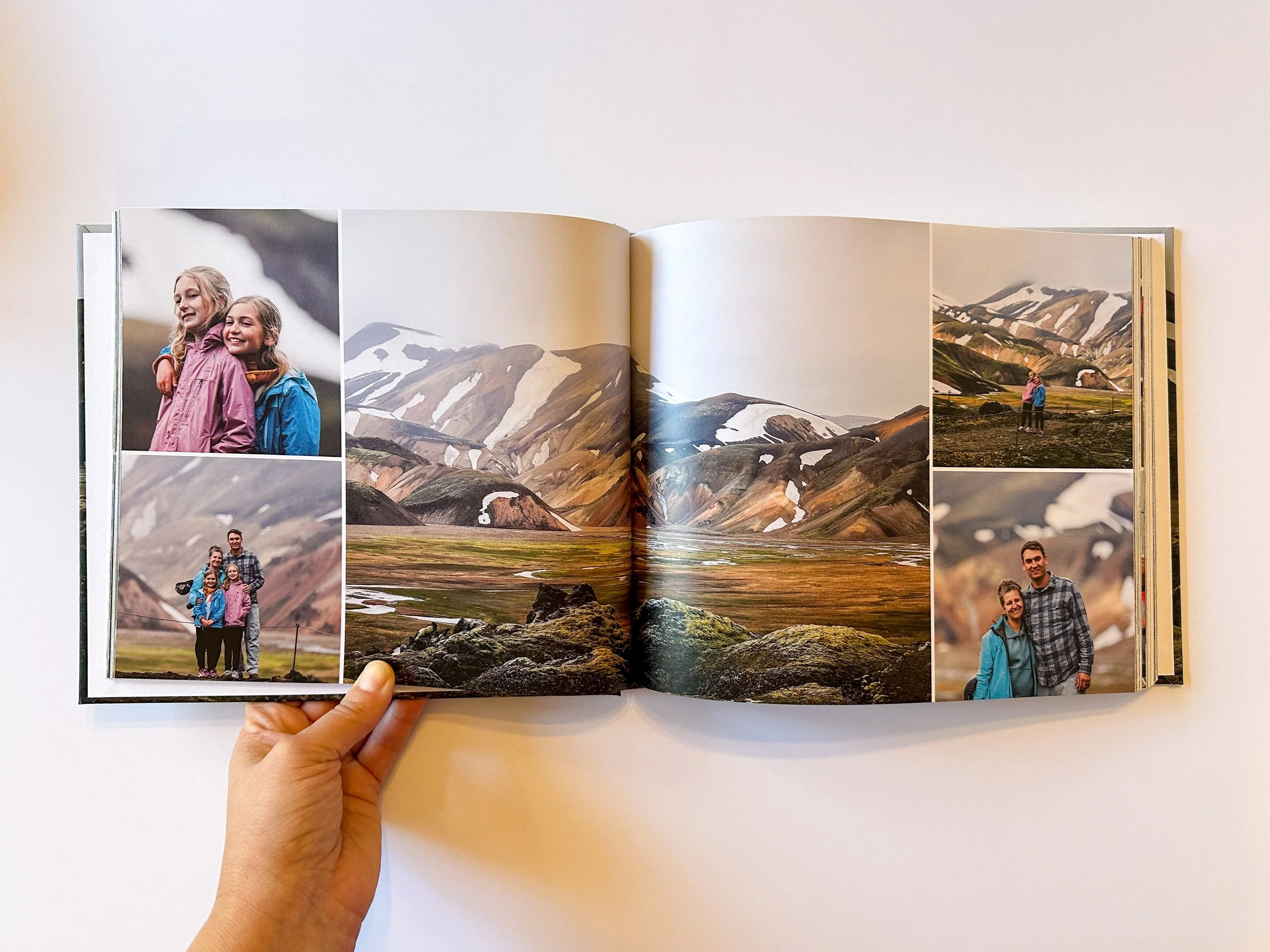 Open photo album showing a landscape with mountains, grassy plain, and rocks, including photographs of a family exploring the outdoors in a mountainous area, with some snow-capped peaks in the background.