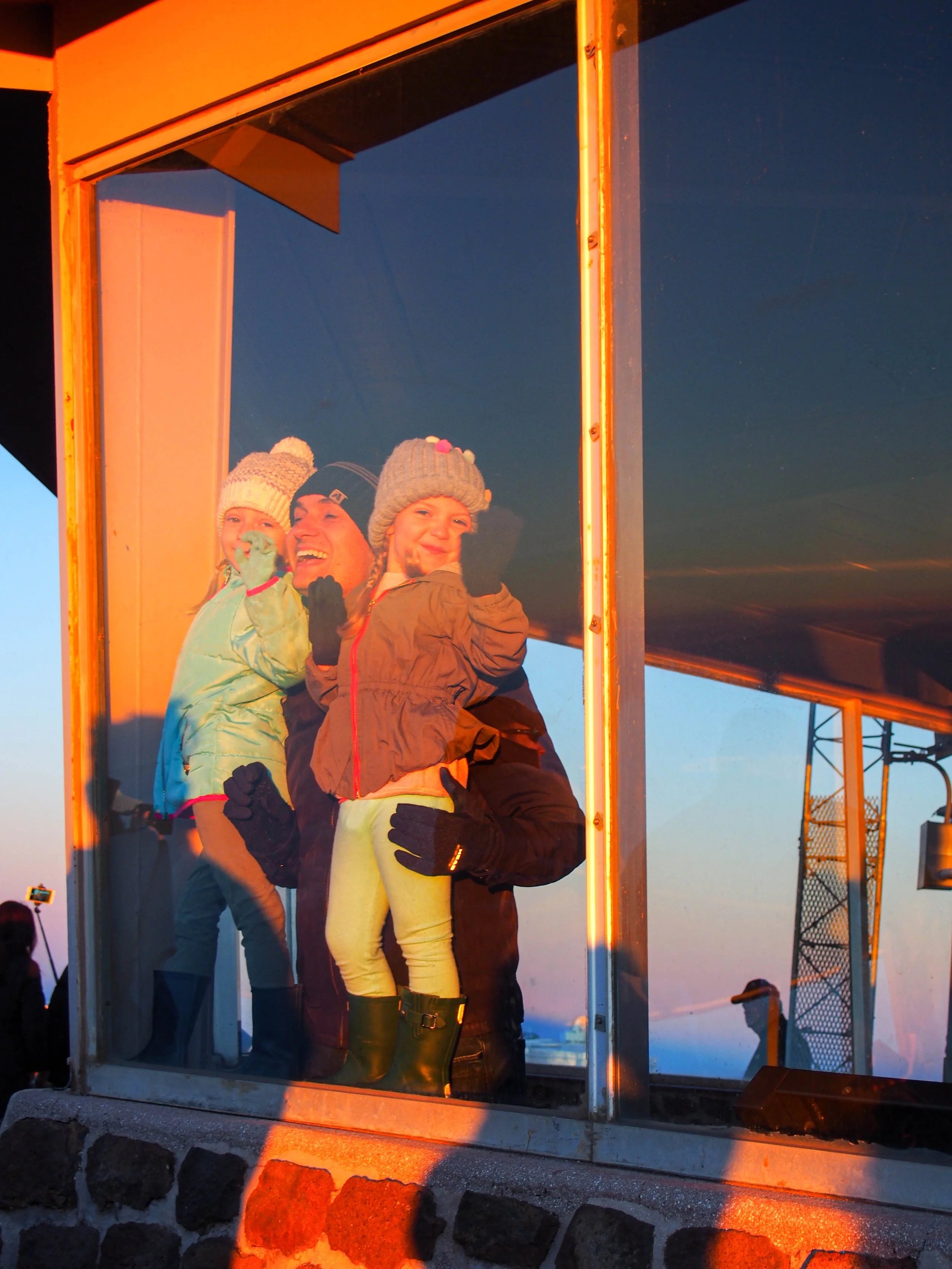 A family looking out the window at the sunrise onto of Haleakala National Park in Maui, Hawaii