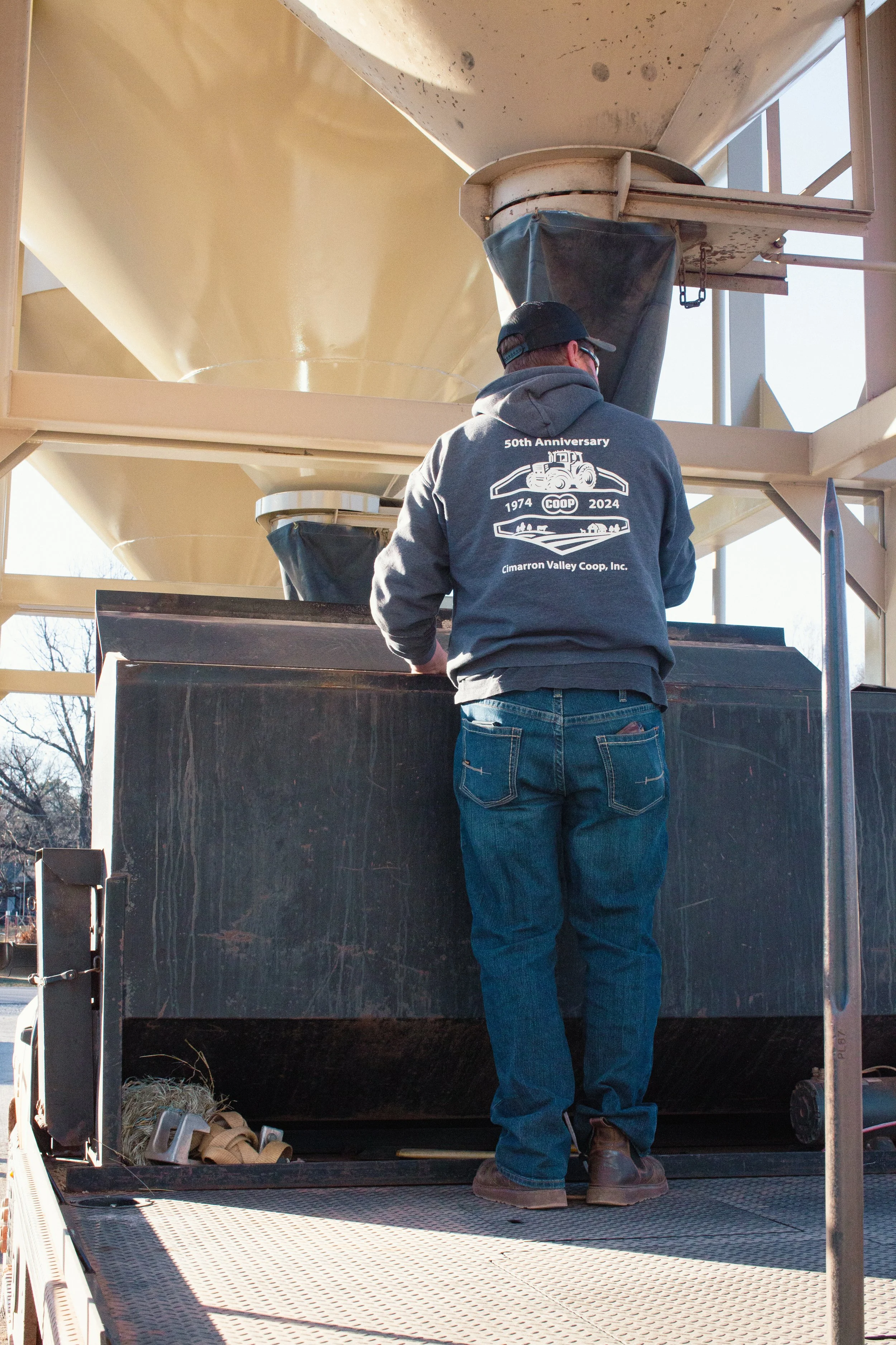 Bulk feed truck filling livestock feeder on a farm in Perkins, Oklahoma.