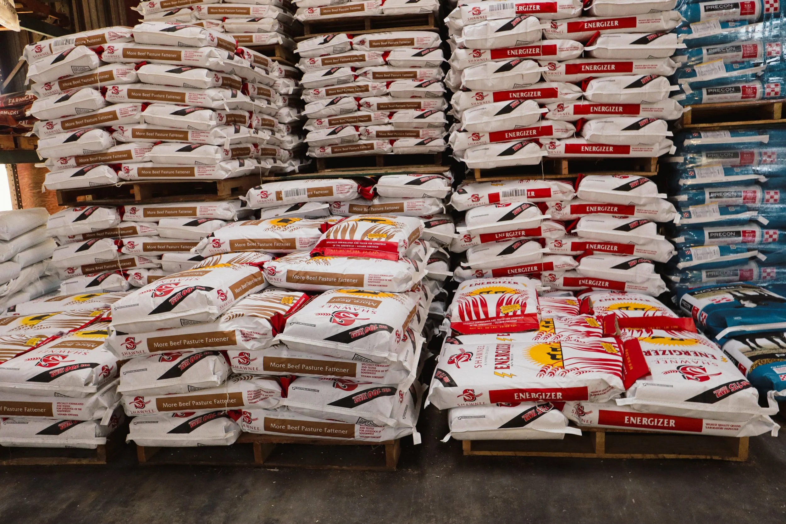 Stacked livestock feed bags including cattle, horse, and show feed available at local co-op.