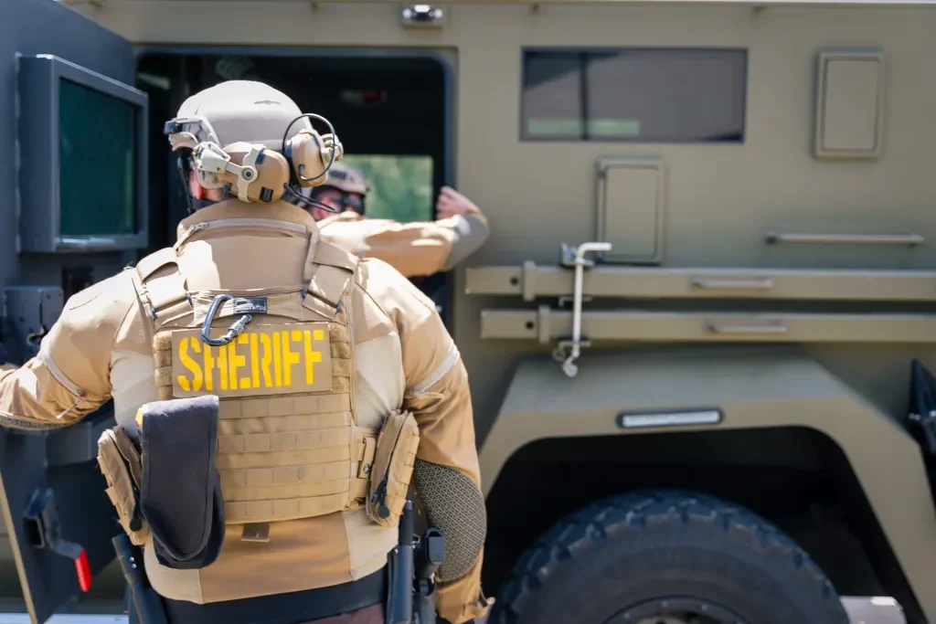 Sheriff deputy in tactical gear loading into an armored vehicle.