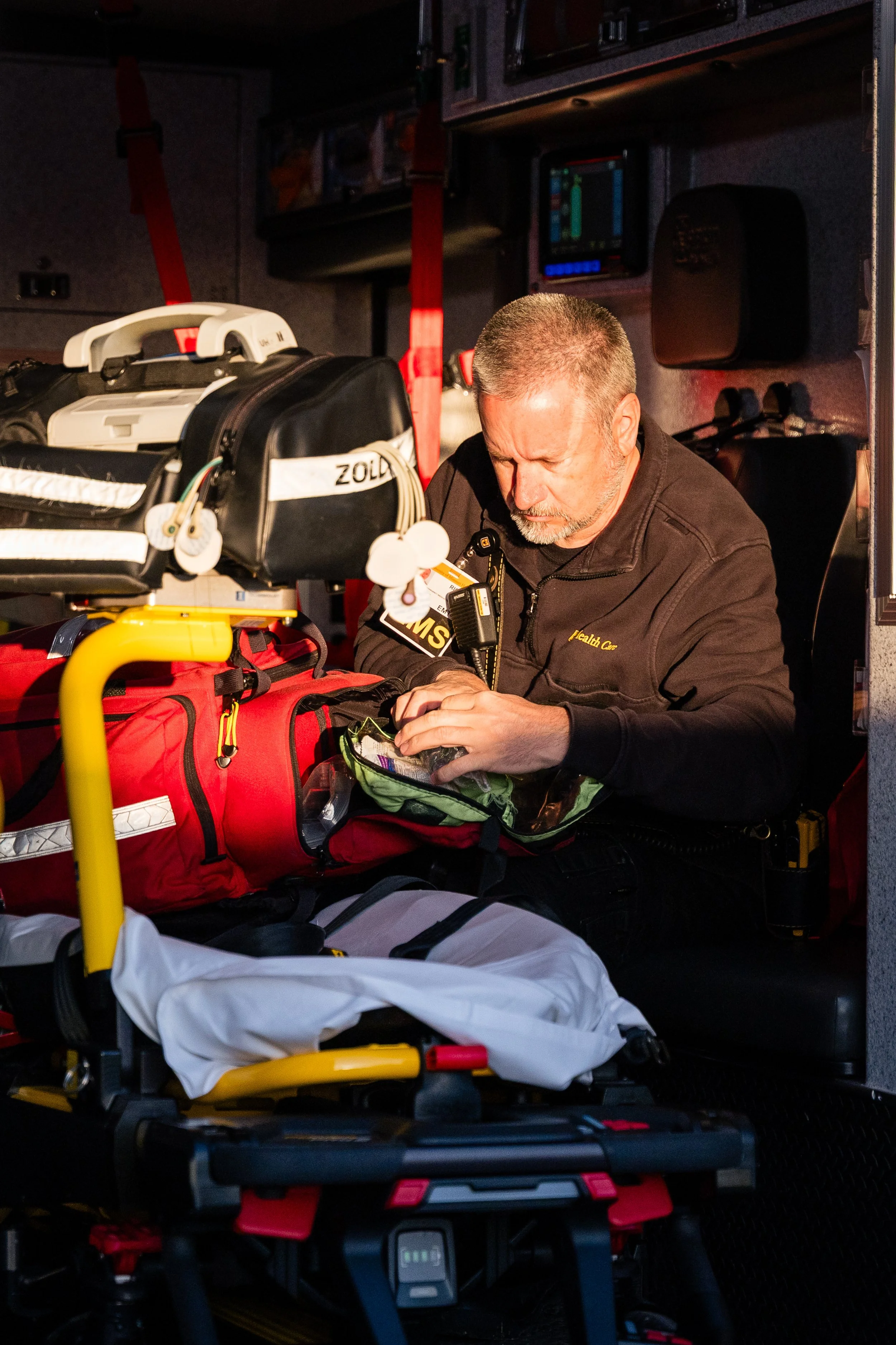 Emergency medical technician preparing medical supplies inside an ambulance.
