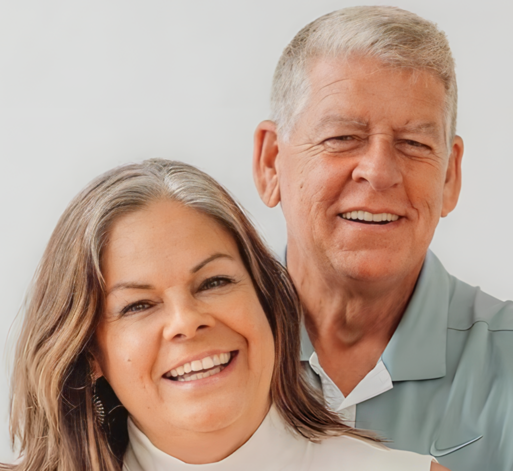 A smiling middle-aged man and woman posing closely together indoors.
