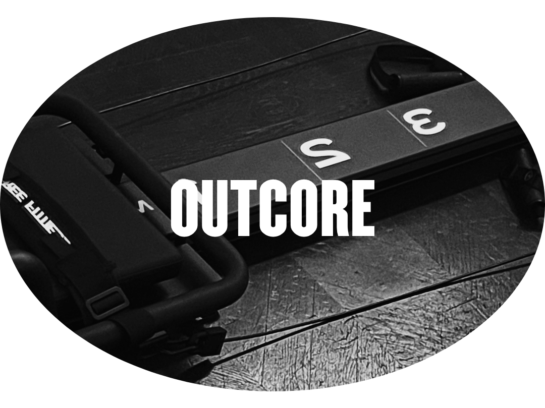 Une planche de bois avec des équipements d'entraînement de CrossFit, notamment un rower, un saut en corde et des plates-formes pour les exercices. Le mot 'OUTCORE' est inscrit en blanc au centre de l'image.