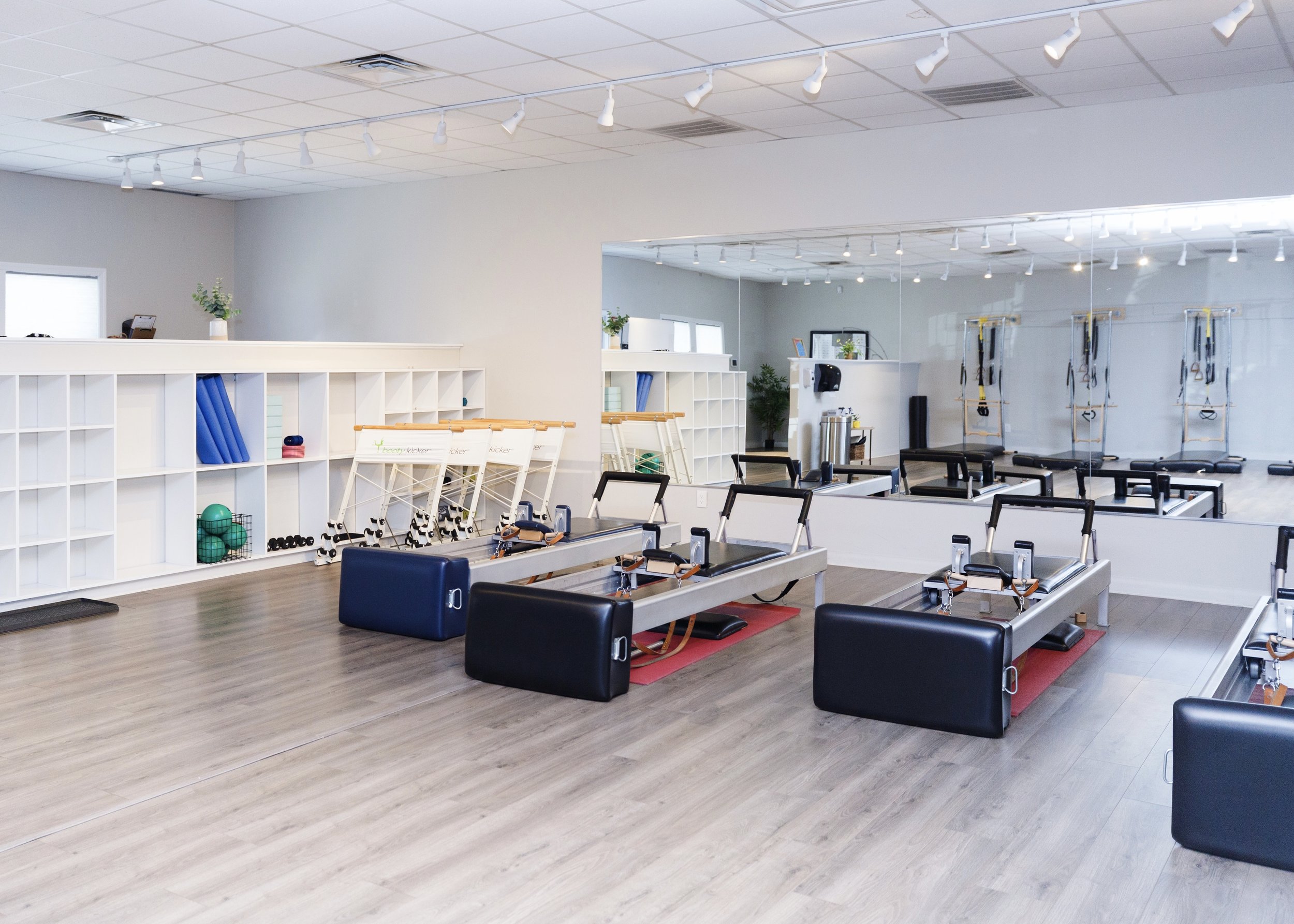 Empty fitness studio with Pilates reformer machines, exercise balls, resistance bands, and mirrored wall