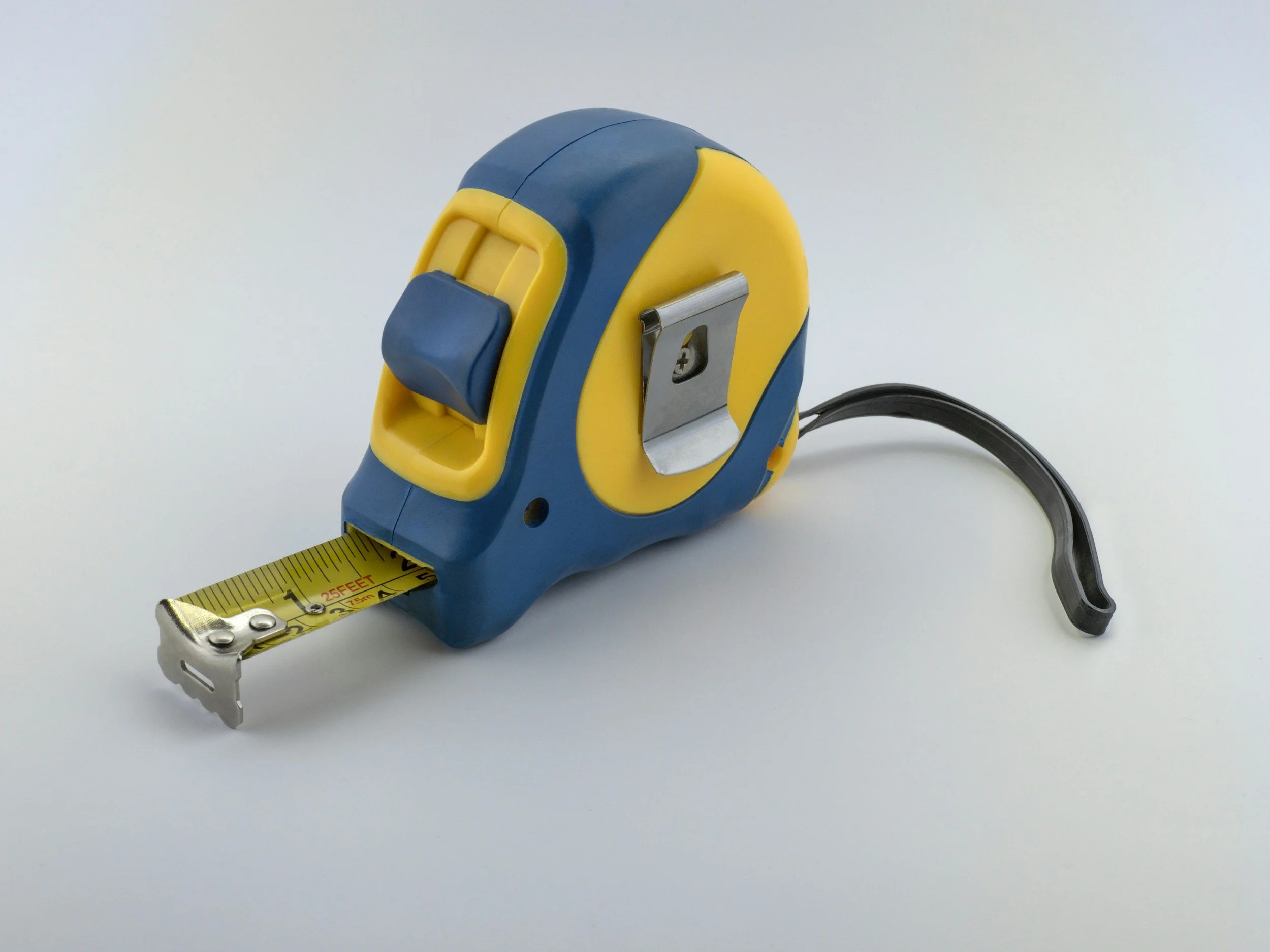 Blue and yellow retractable tape measure extended to about 6 inches on a white background.