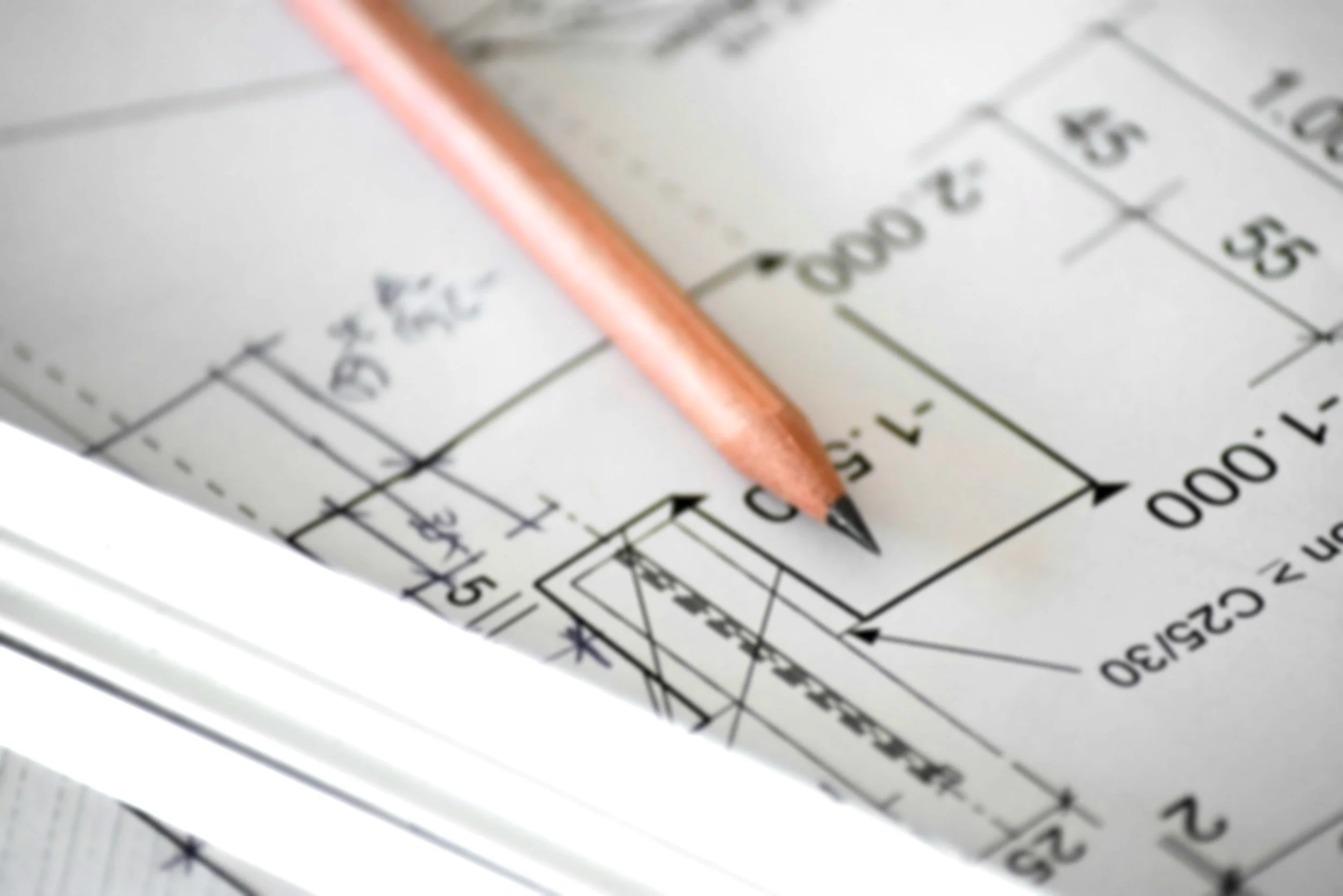 Close-up of an architectural blueprint or technical drawing with a pencil resting on it.