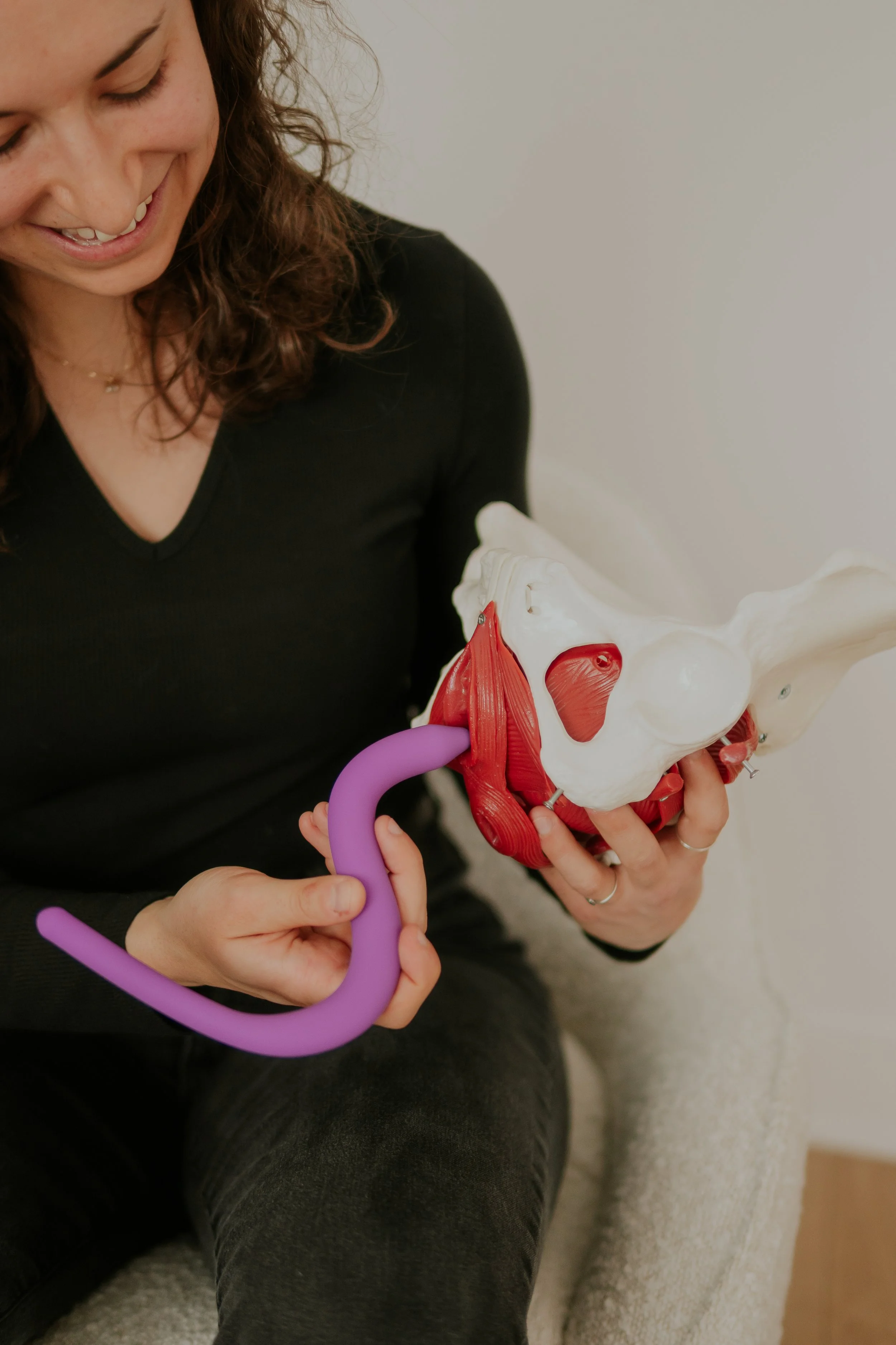 Woman holding a pelvis model with a purple stethoscope.