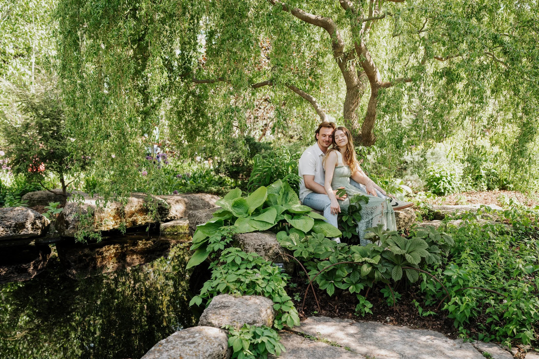 Couple sitting together beside a garden pond surrounded by lush greenery at Olbrich Botanical Gardens in Madison, Wisconsin.