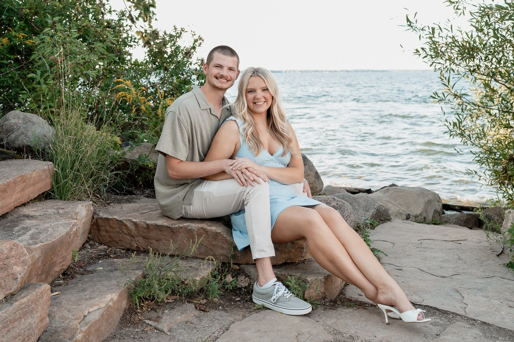 Couple sitting together along the lakeshore during an engagement session at Picnic Point in Madison, Wisconsin.