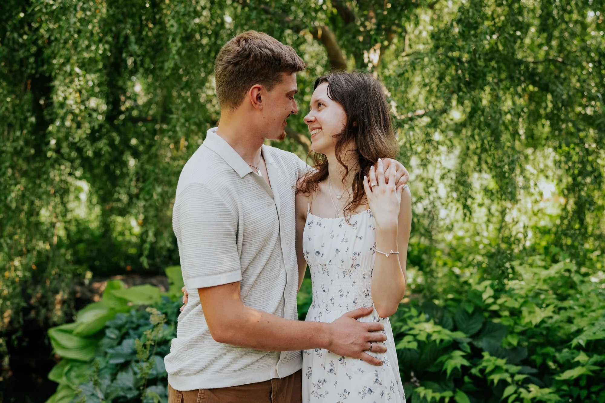 Portrait of couple around greenery just after a surprise proposal.