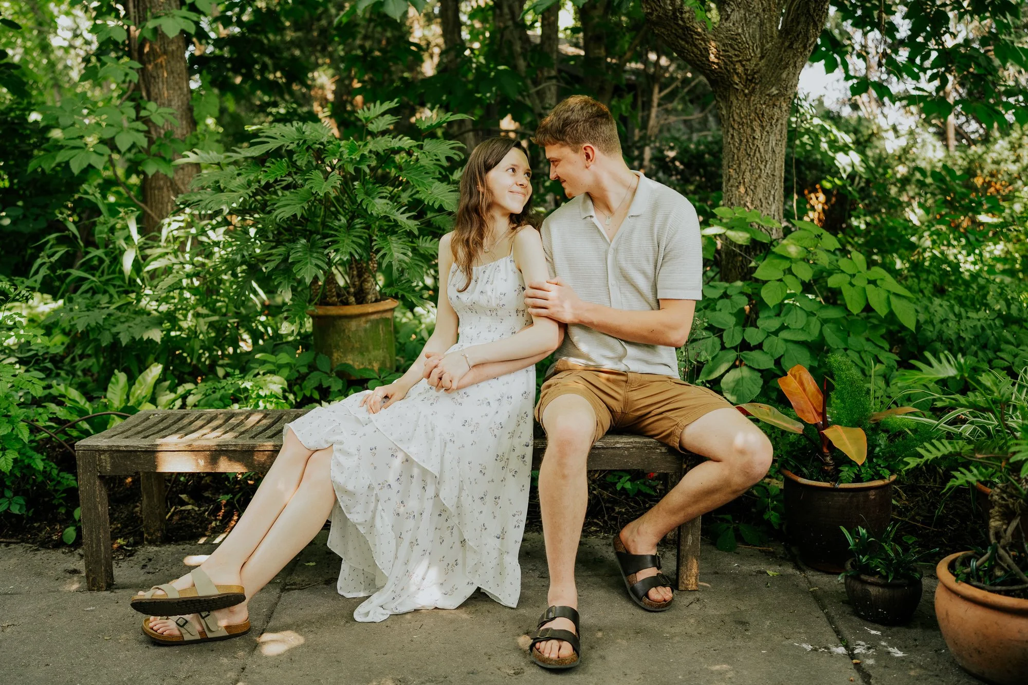 Sweet portrait of an engaged couple sitting on bench in the gardens