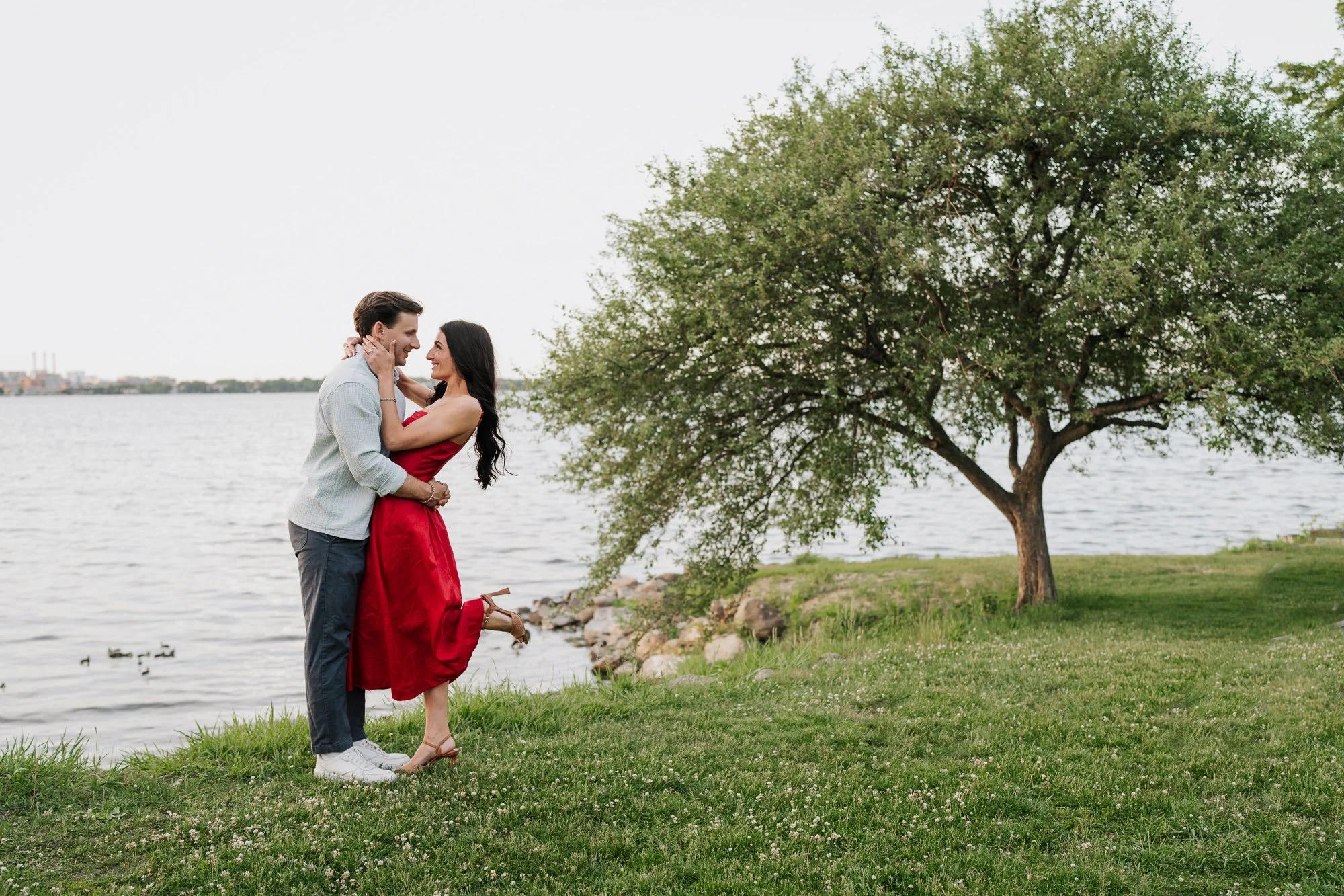 Couple embracing beside Lake Monona at Olin Park during their Madison engagement session.