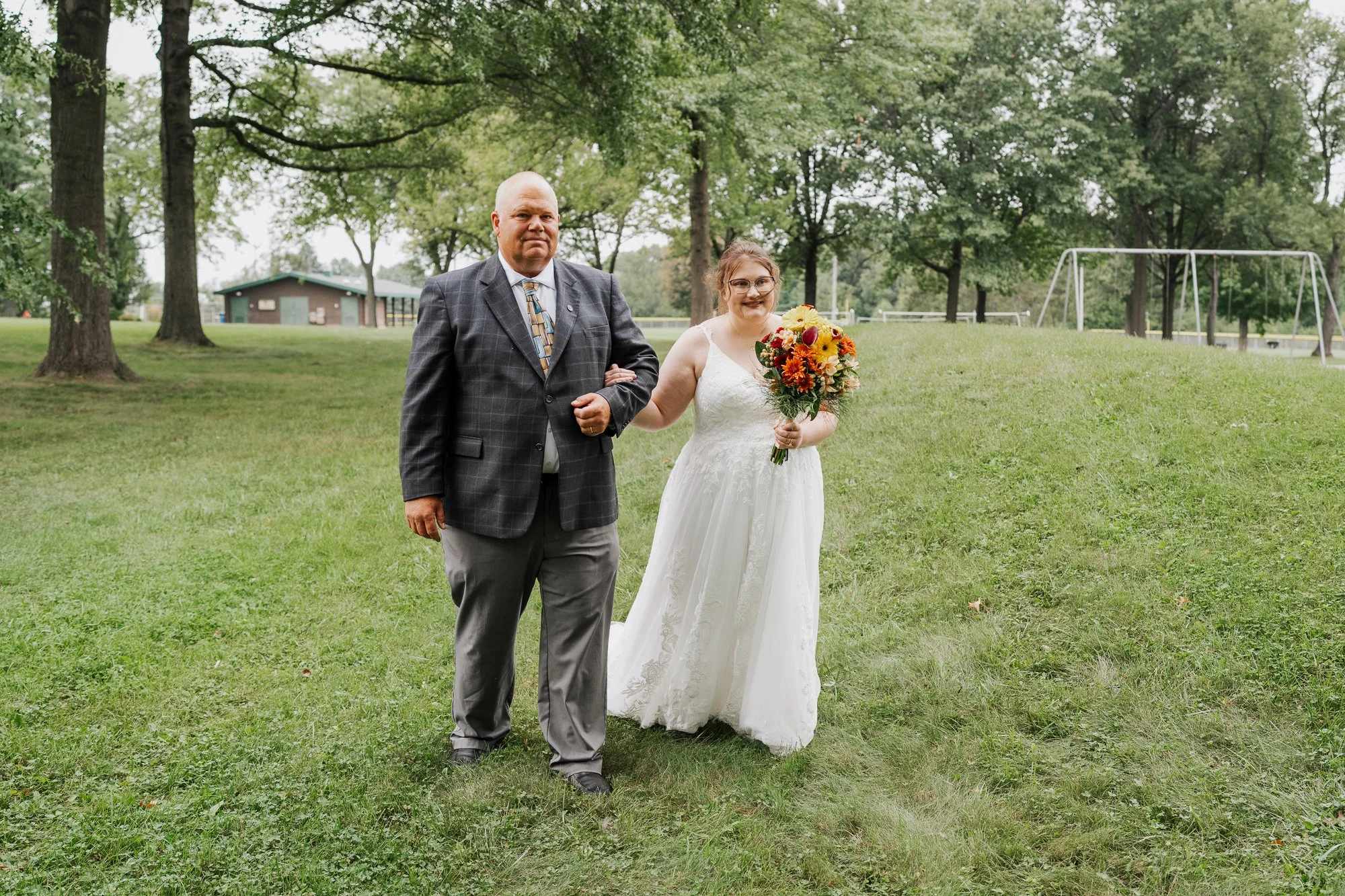 Bride walking with her father to an intimate outdoor wedding ceremony