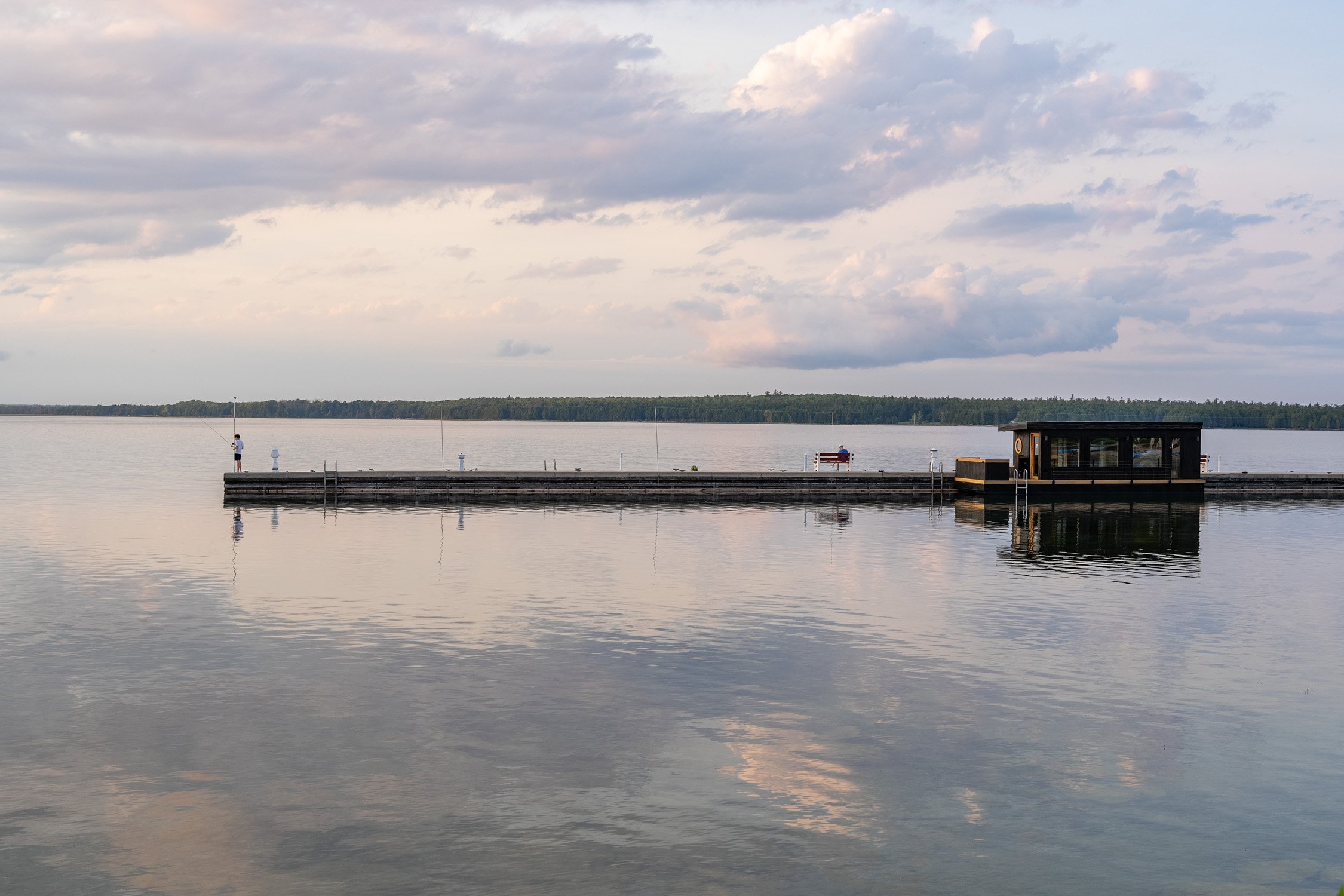 A dock in door county with the colorful clounds and sky reflecting in the water.