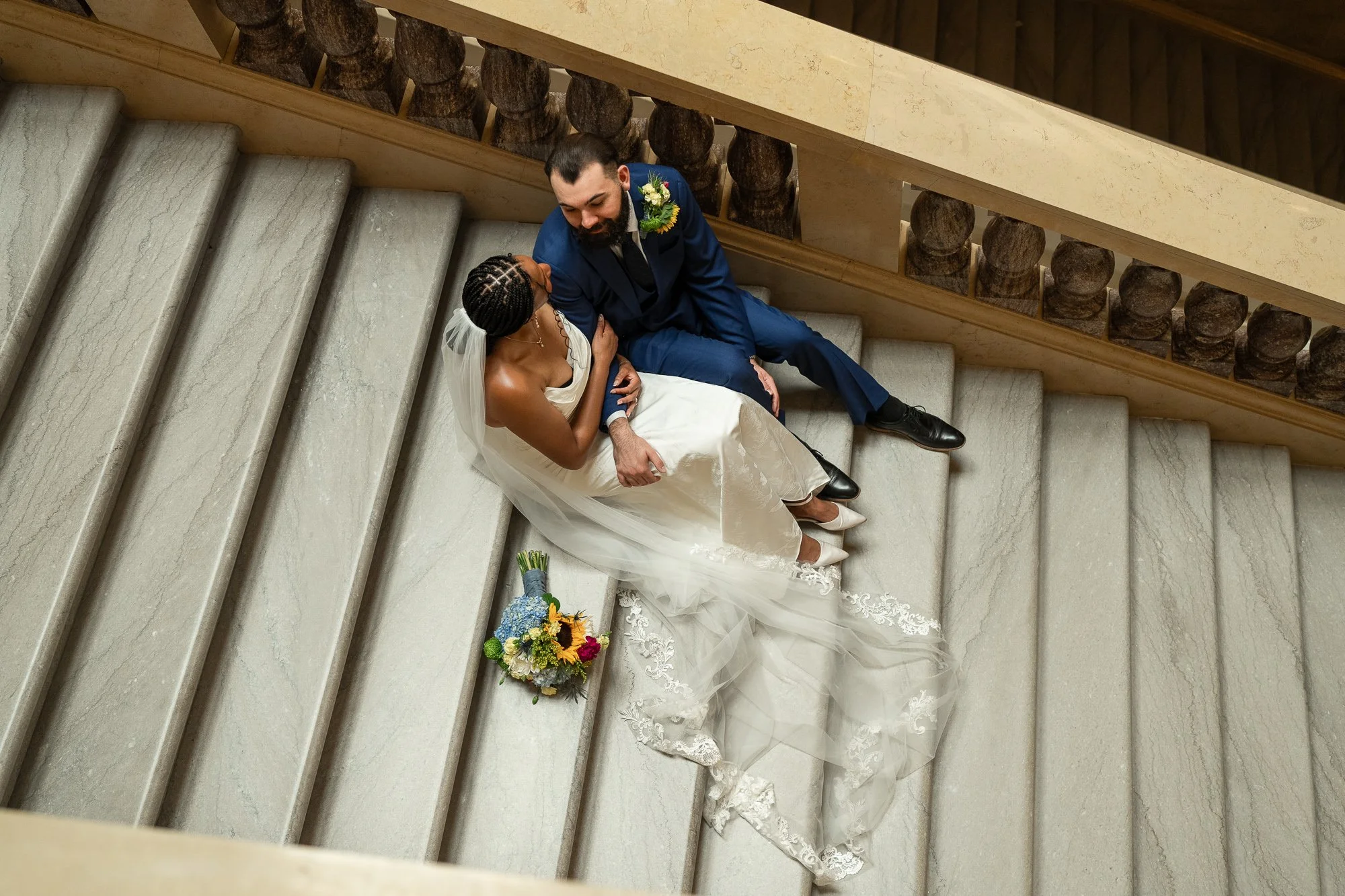 Couple sitting together on a marble staircase inside the Wisconsin State Capitol during their Madison elopement.
