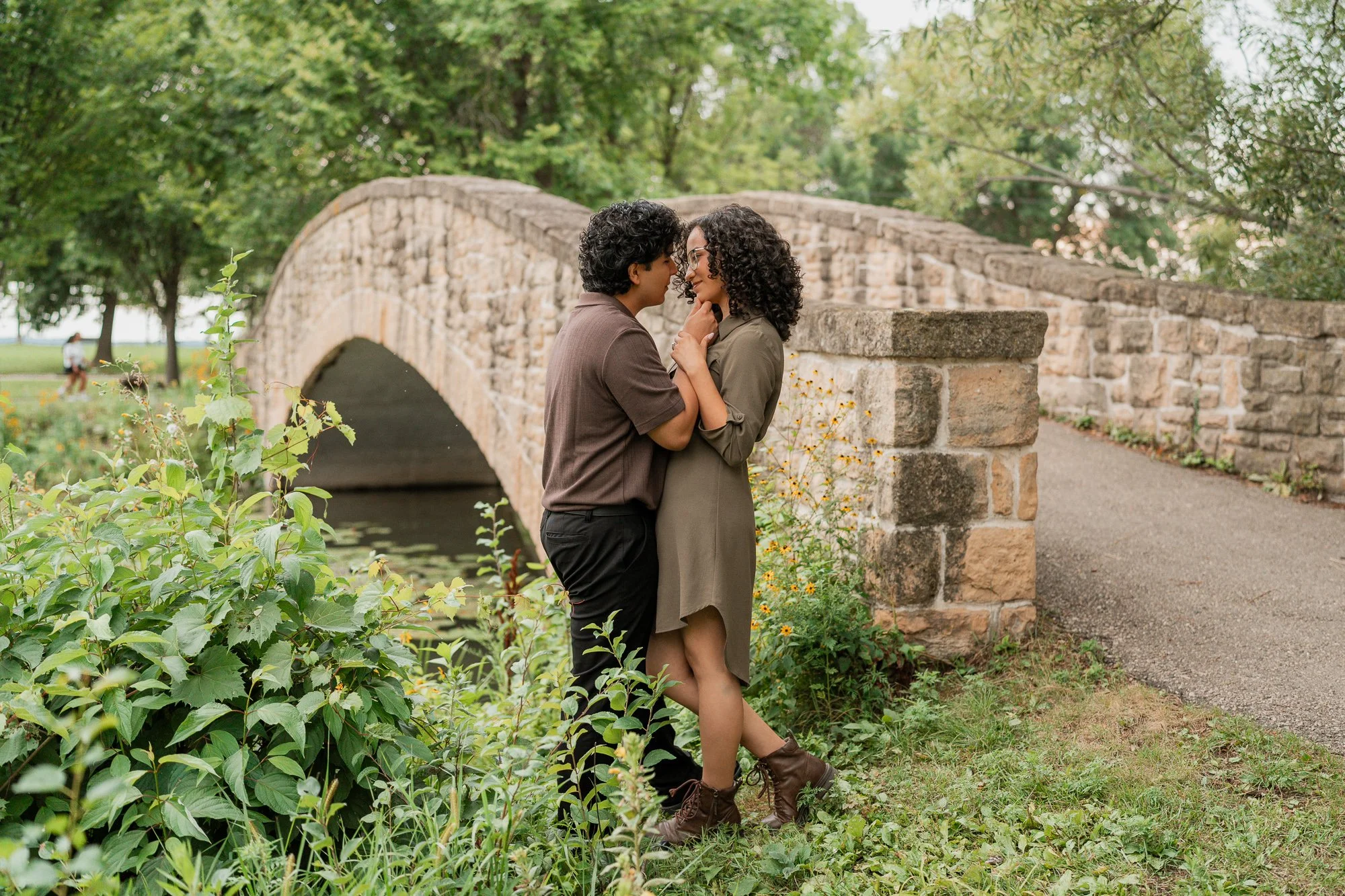 Couple embracing beside a stone bridge during an engagement session at Tenney Park in Madison, Wisconsin.