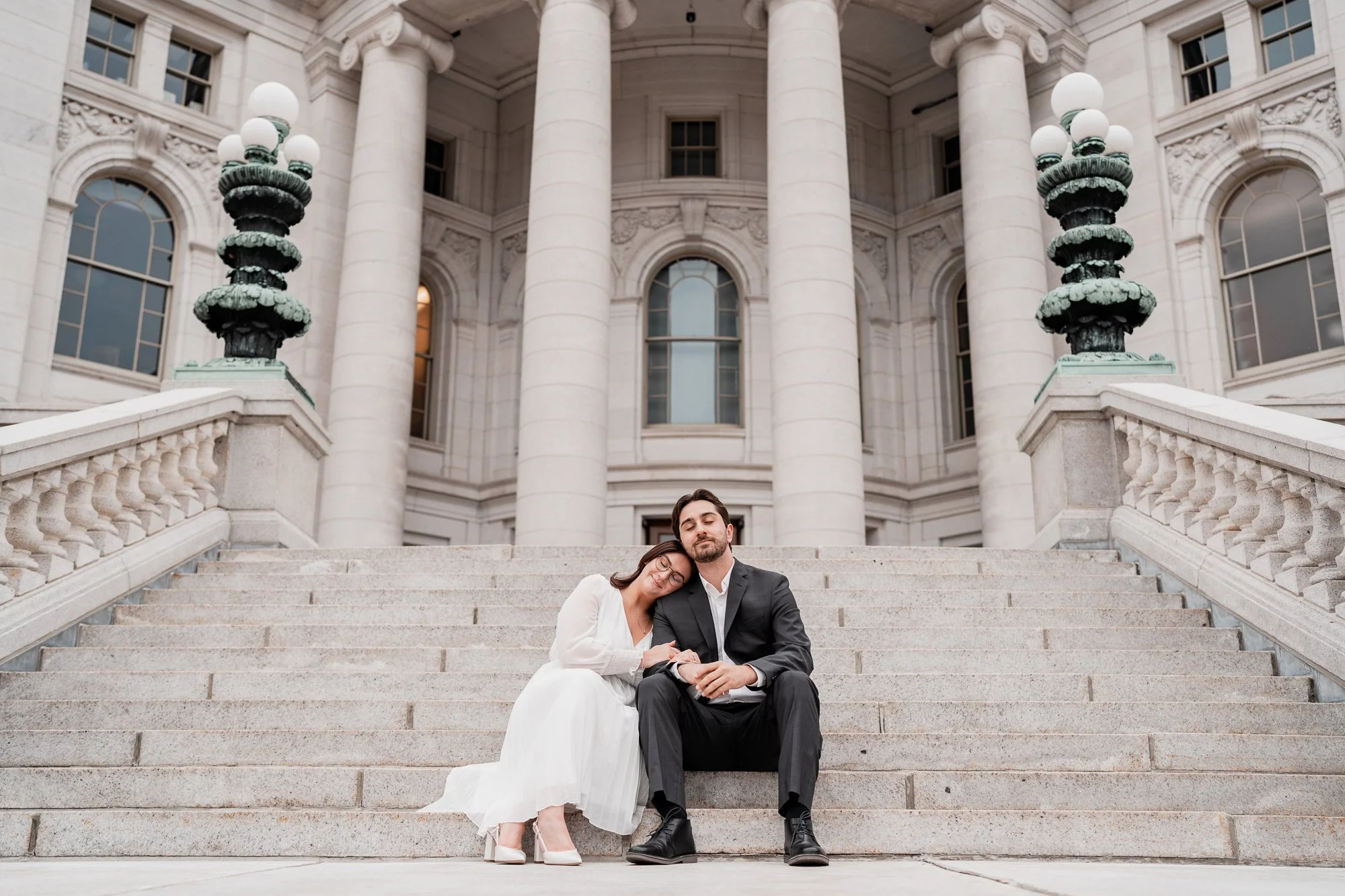 Couple sitting together on the steps of the Wisconsin State Capitol during an engagement session in downtown Madison, Wisconsin.