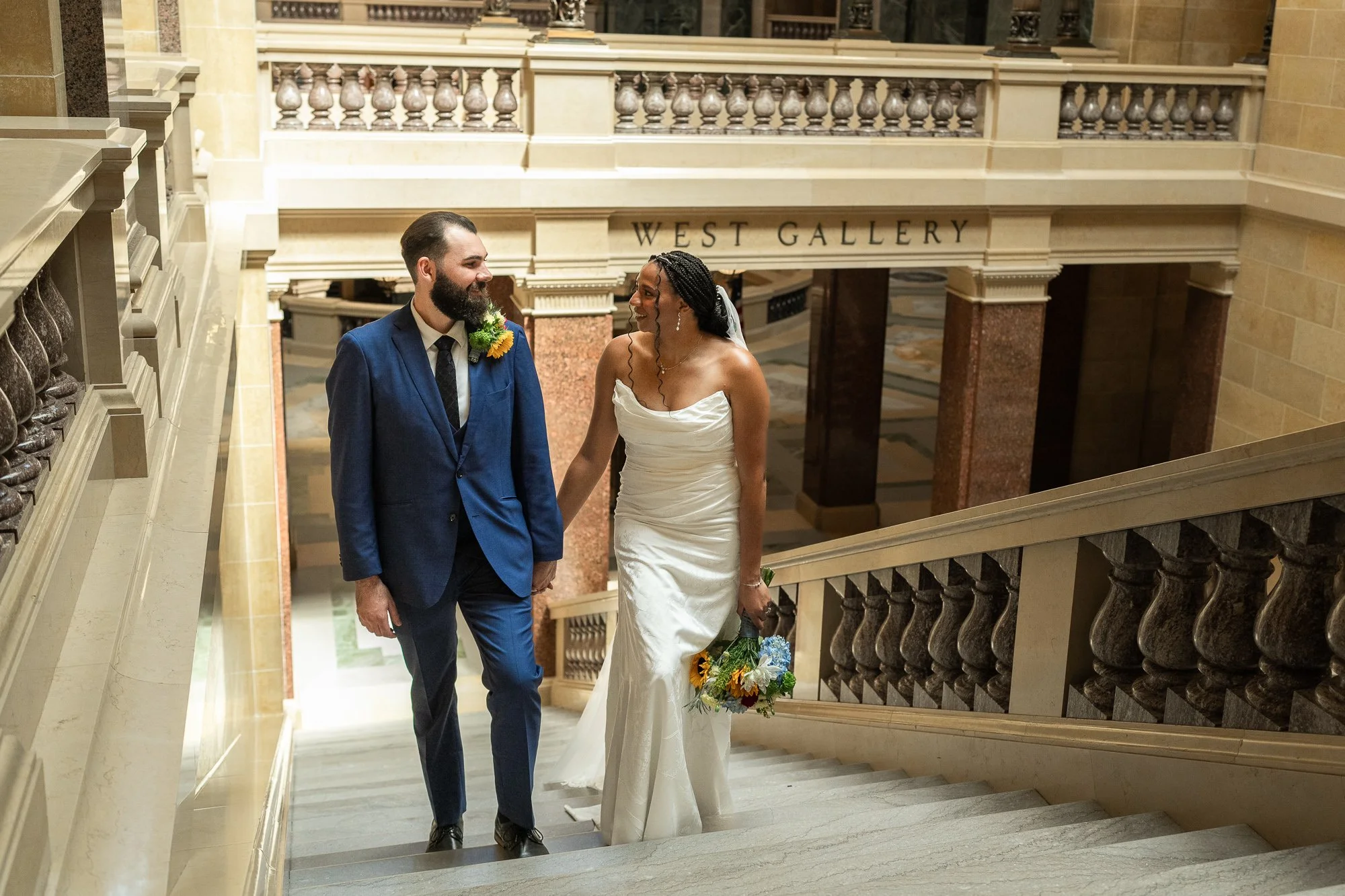 Elopement couple walking up stairs in the madison capital in wedding dress and blue suit.