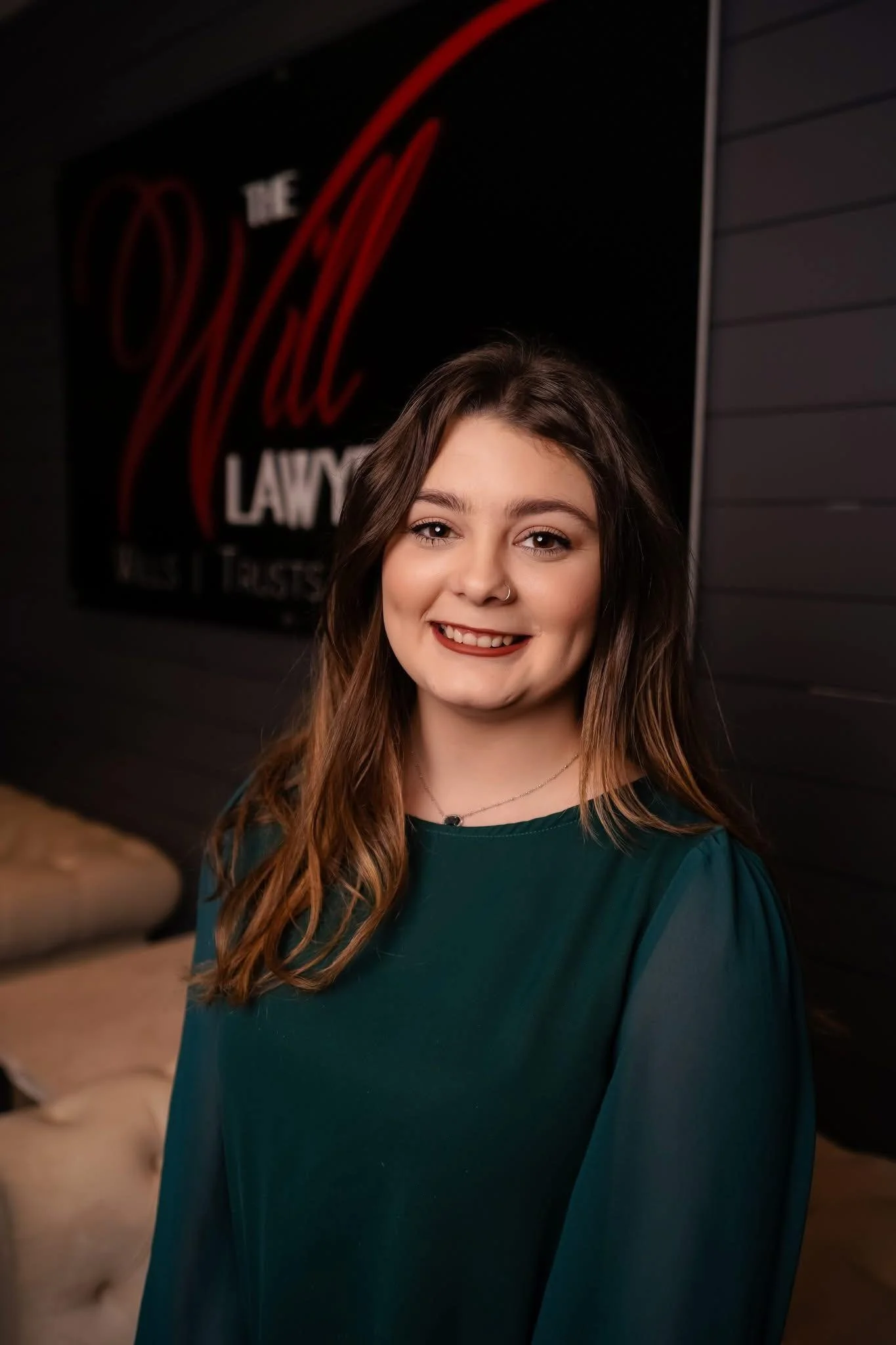 A young woman with long brown hair smiling in front of a dark background with red and white text.
