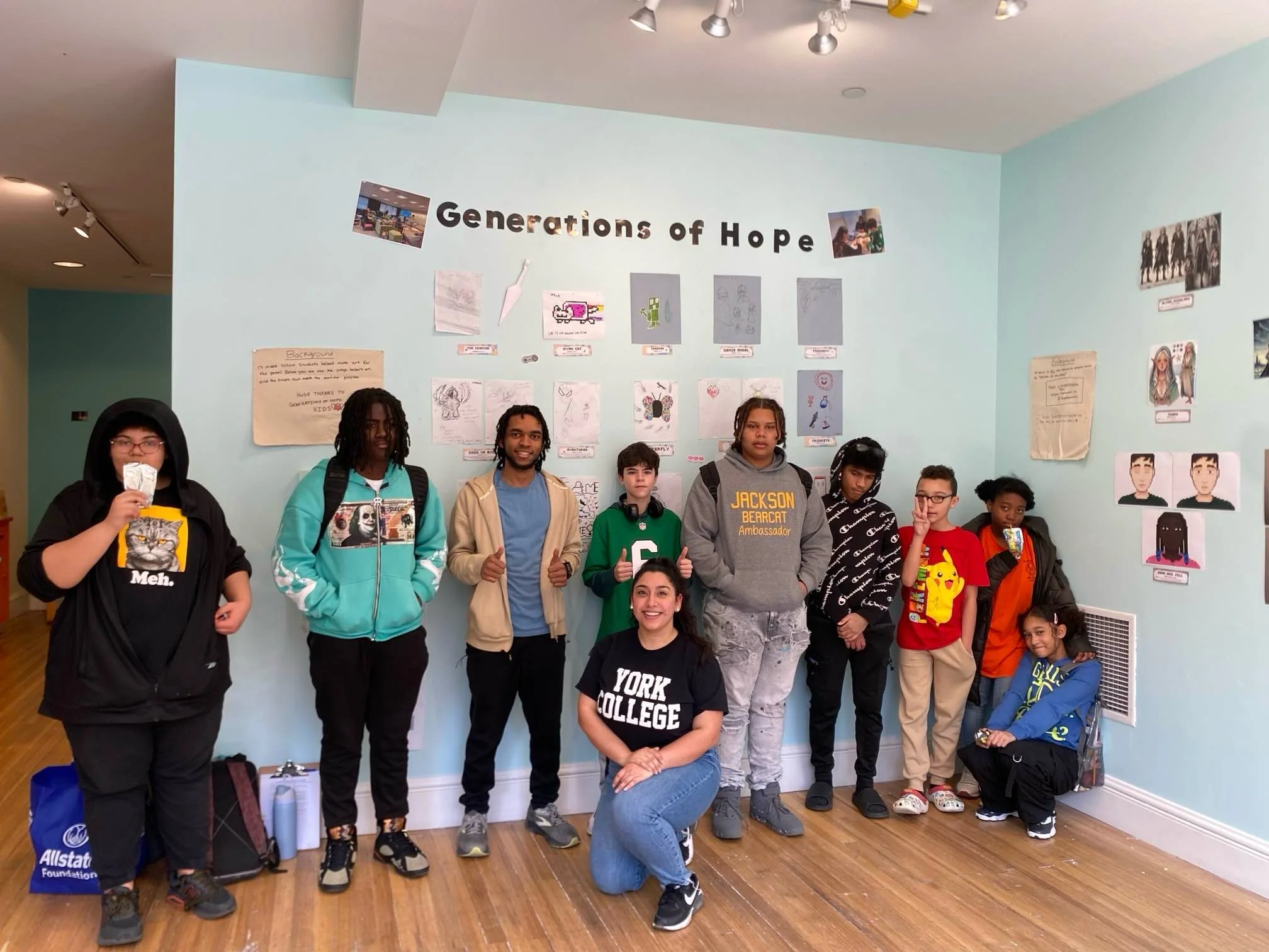 Group of ten diverse children and teenagers posing together indoors, standing in front of a light blue wall decorated with photos, drawings, and posters, with the words "Generations of Hope" displayed above.