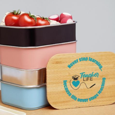 A storage container with three drawers holding tomatoes, radishes, and other vegetables. Next to the container, a wooden lid with a teacher-themed design and the phrase 'Never stop learning because life never stops teaching'.