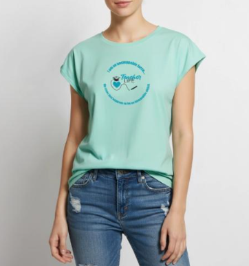 A woman wearing a light green t-shirt with 'Teacher Life' design, paired with distressed blue jeans.