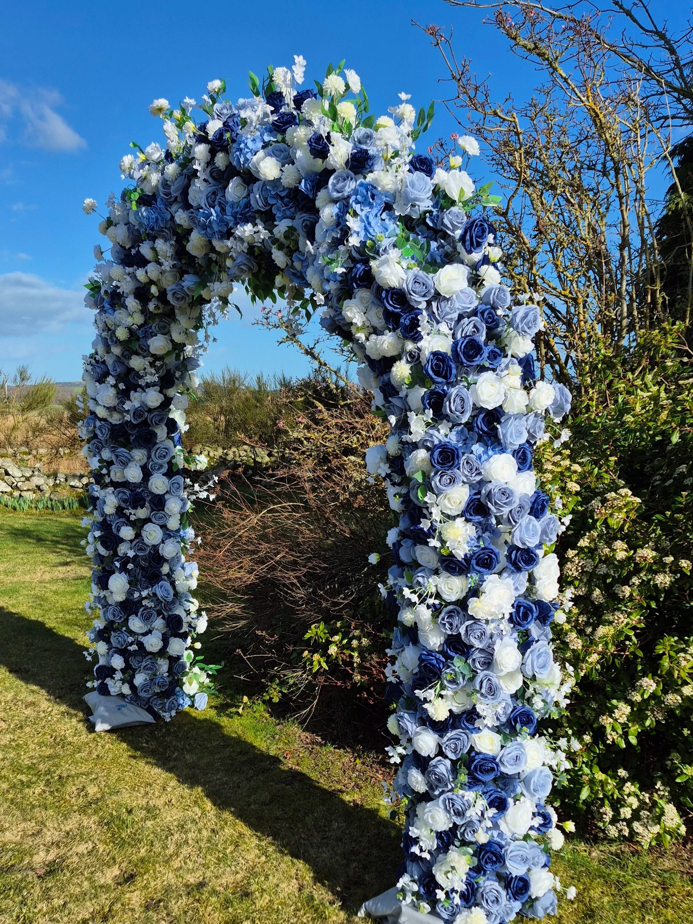 Blue floral midnight serenade arch set up in the sunshine on grass