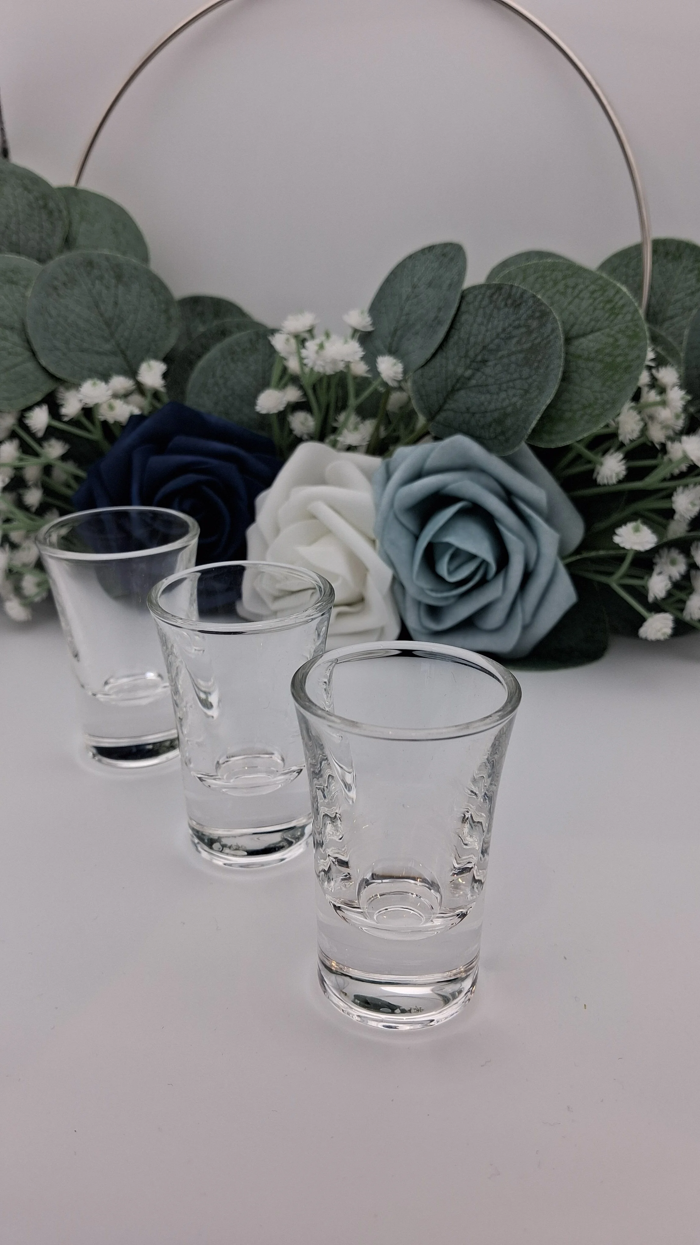 3 25ml shot glasses arranged in front of blue flowers