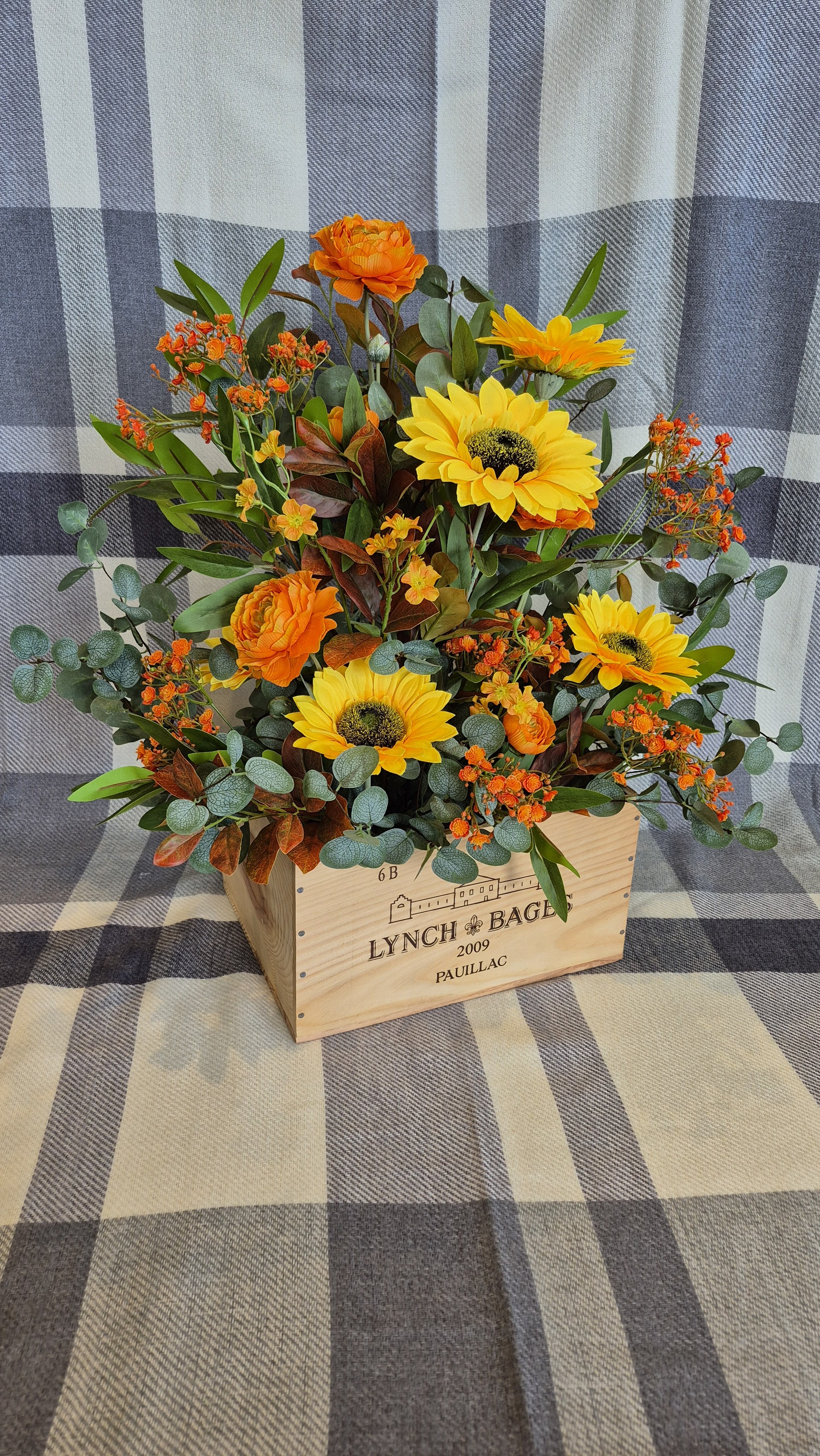 Autumn orange and greens artificial floral floor display in a vintage wine box
