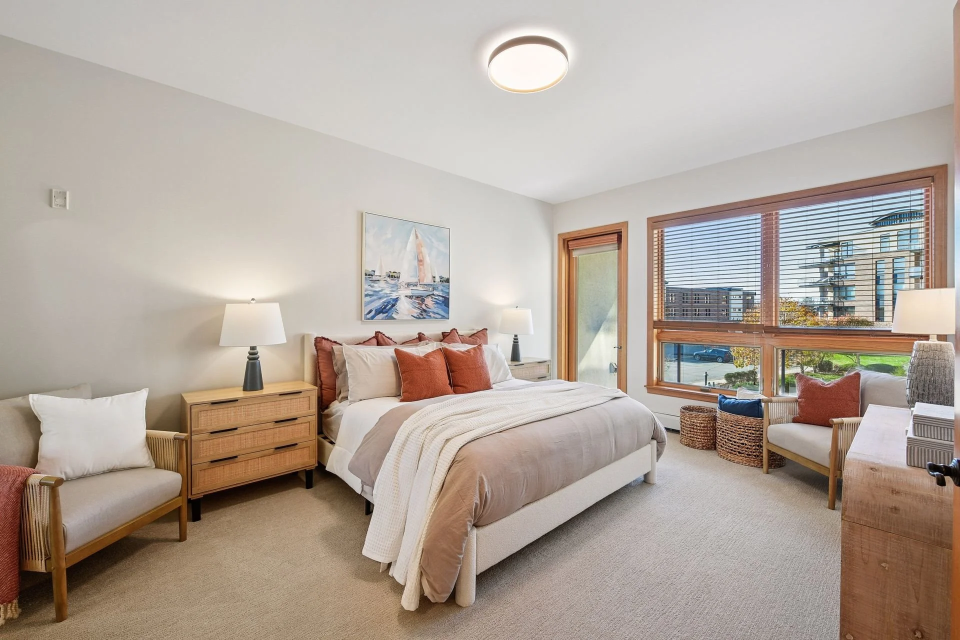 A cozy bedroom with large windows with wooden blinds showing a cityscape outside.