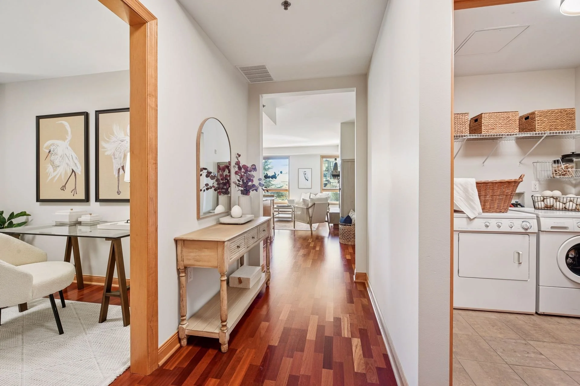View of living room and laundry area in a home with hardwood flooring.