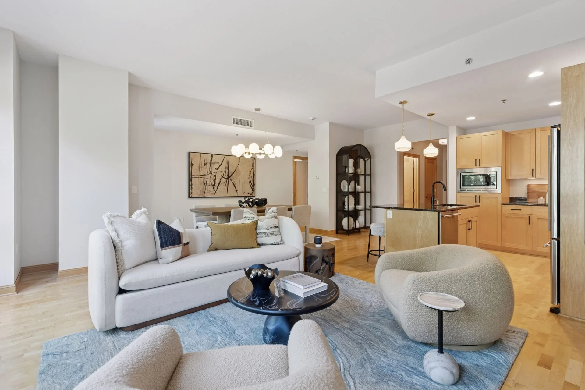Open-concept living room and kitchen with neutral tones and wooden flooring.