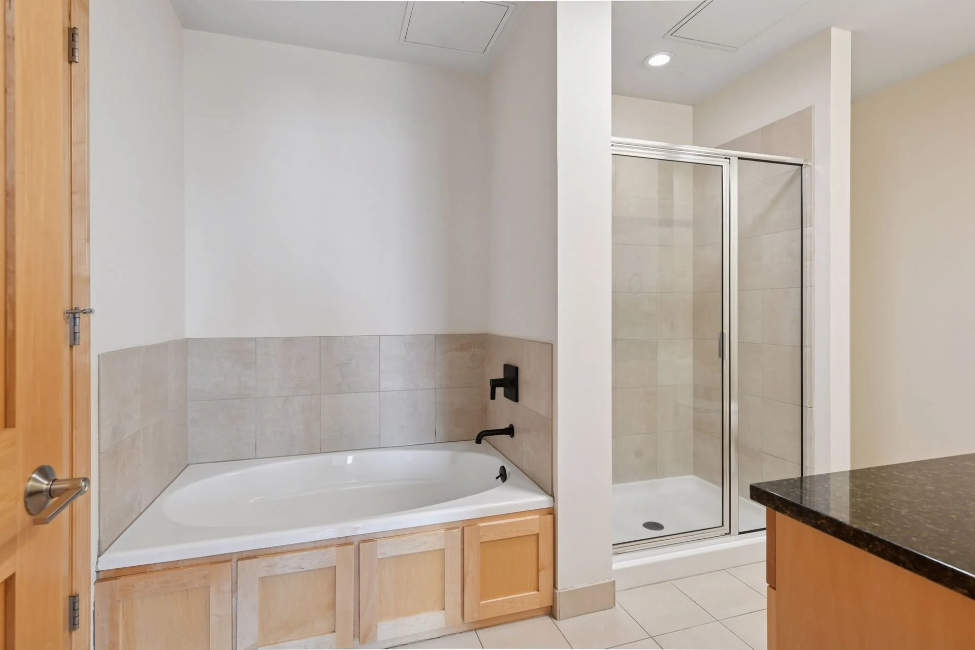 Bathroom with a corner bathtub, a walk-in shower with glass door, and a granite countertop.