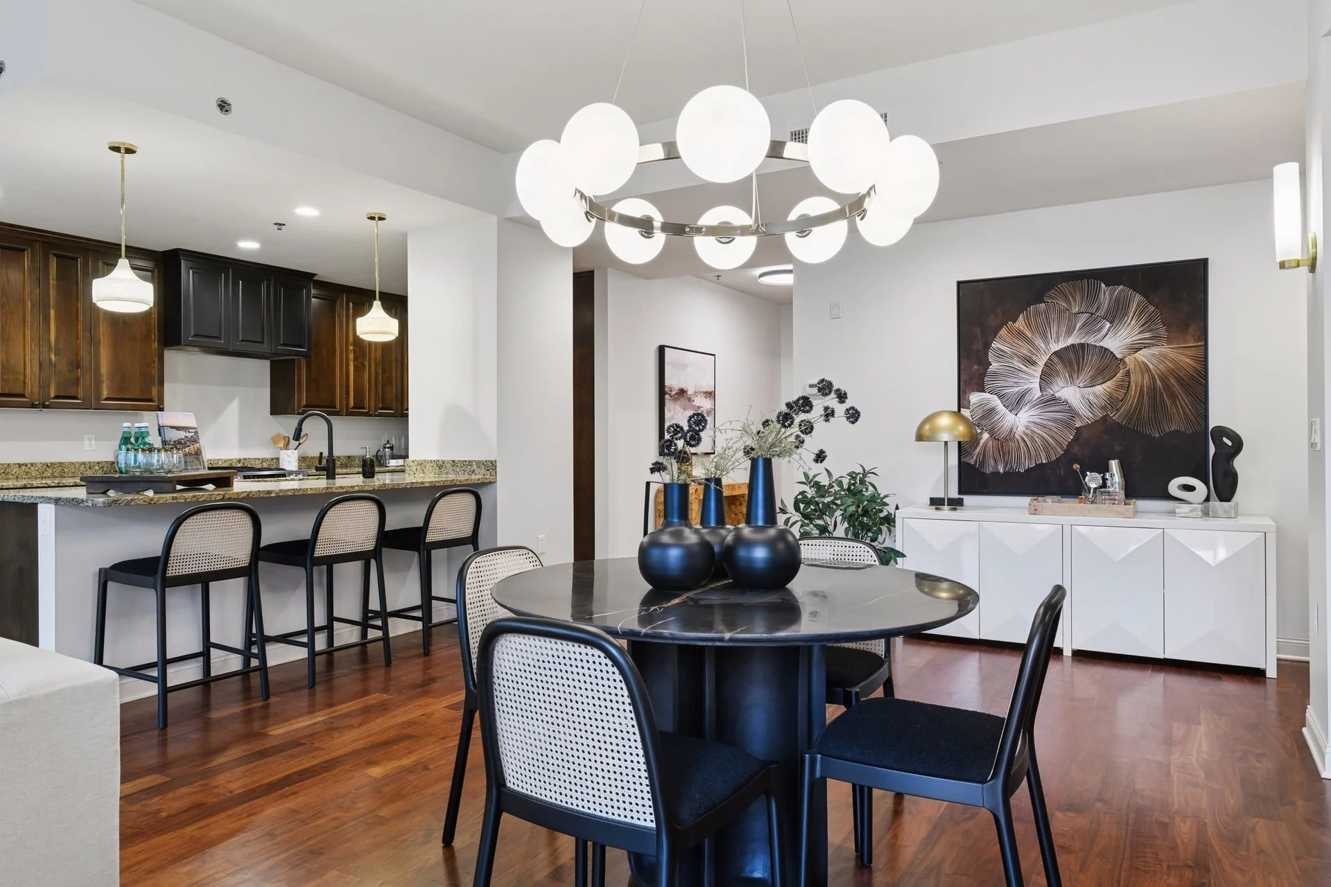 Modern dining room and kitchen wooden cabinetry, granite countertops, and pendant lighting.