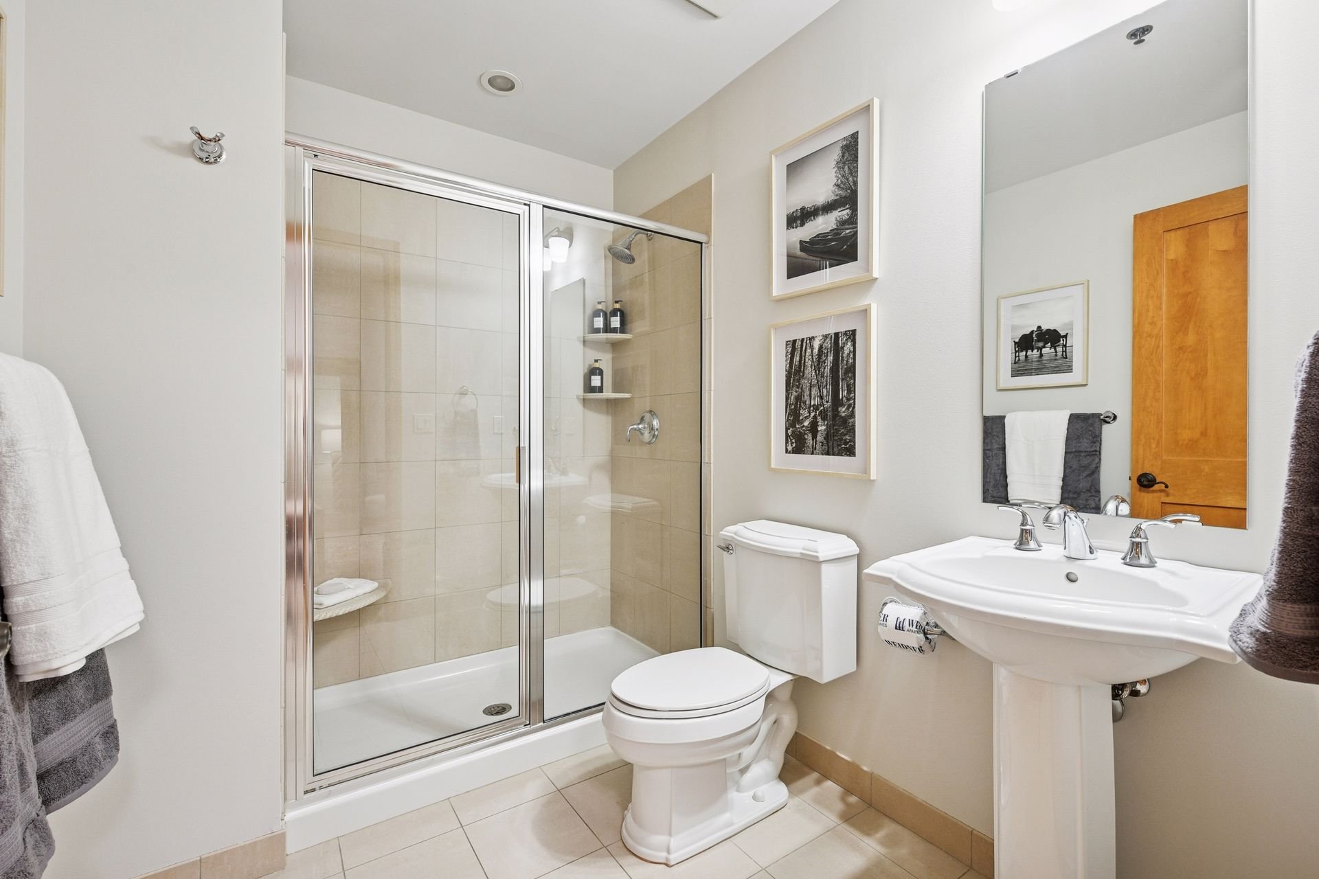 Bathroom with a walk-in shower, toilet, and pedestal sink.