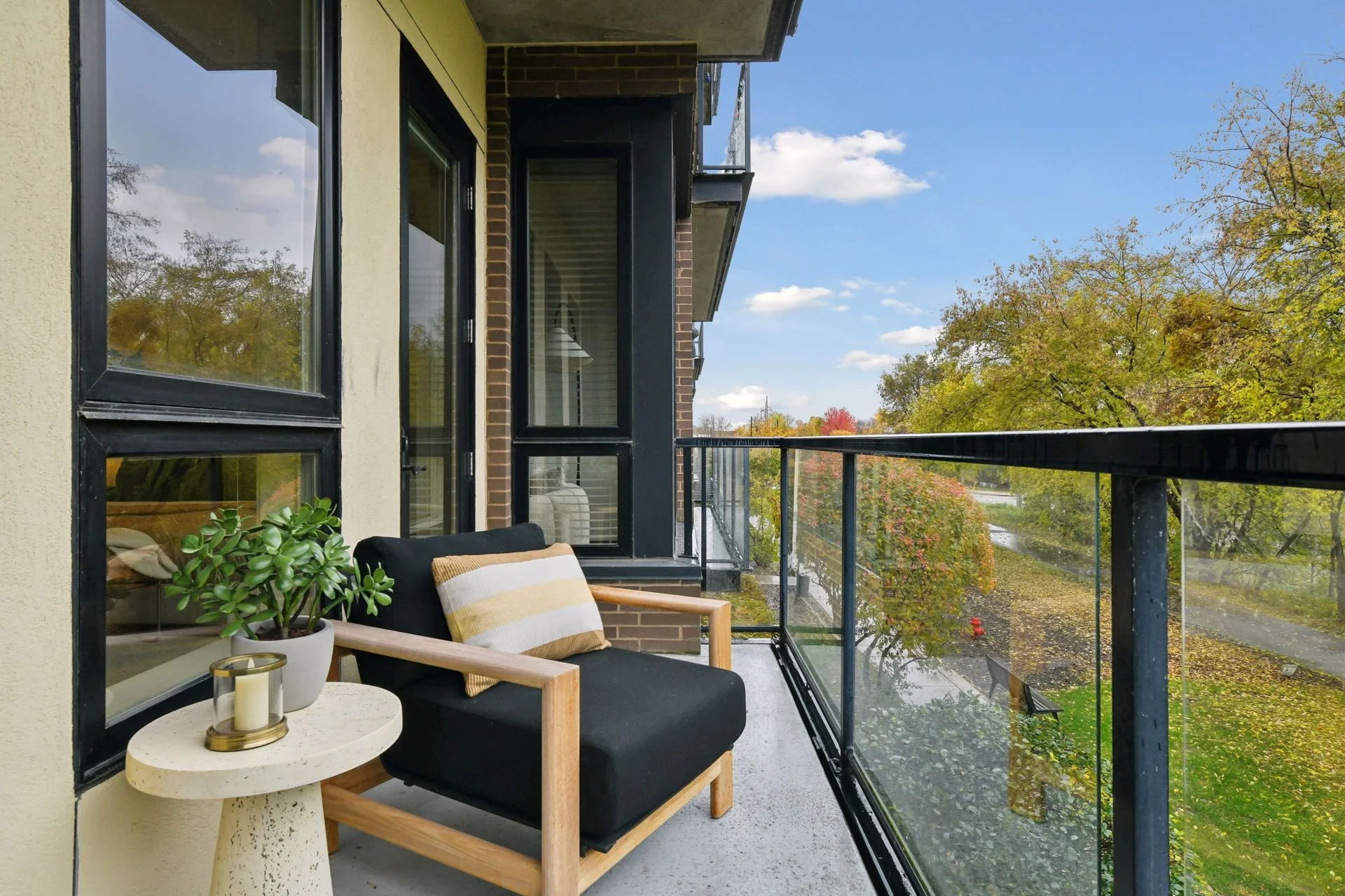 A balcony overlooking trees with autumn foliage and a partly cloudy sky.