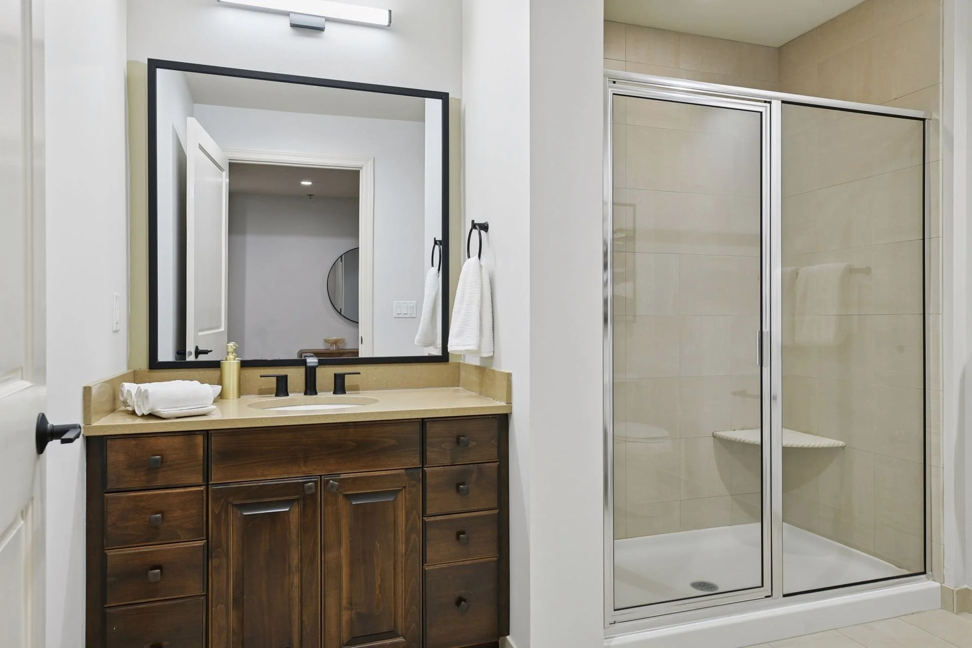 Bathroom with a wooden vanity, a mirror, a sink, and a shower with glass doors.