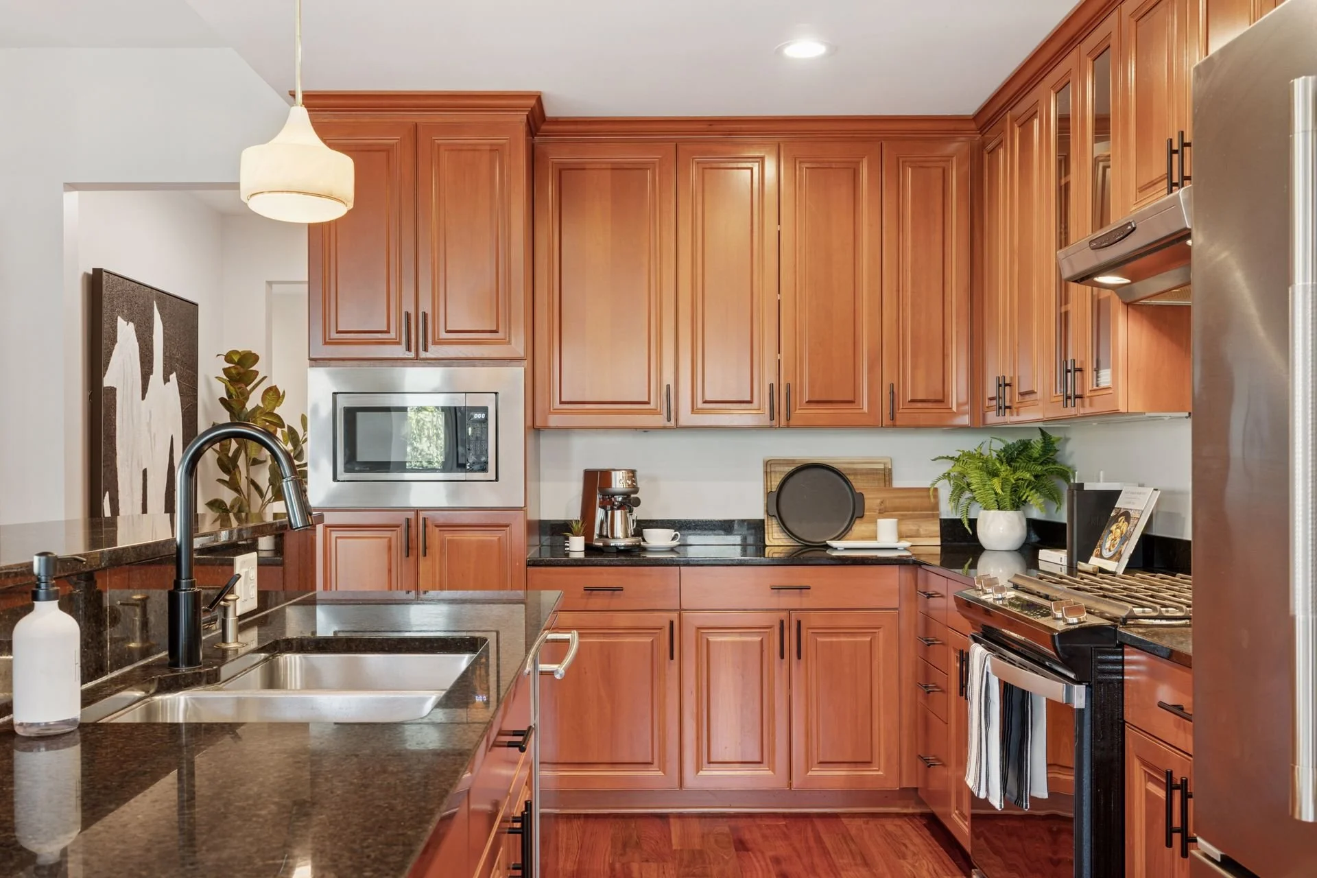 Kitchen with wooden cabinets, black granite countertops, stainless steel appliances, and a double sink.