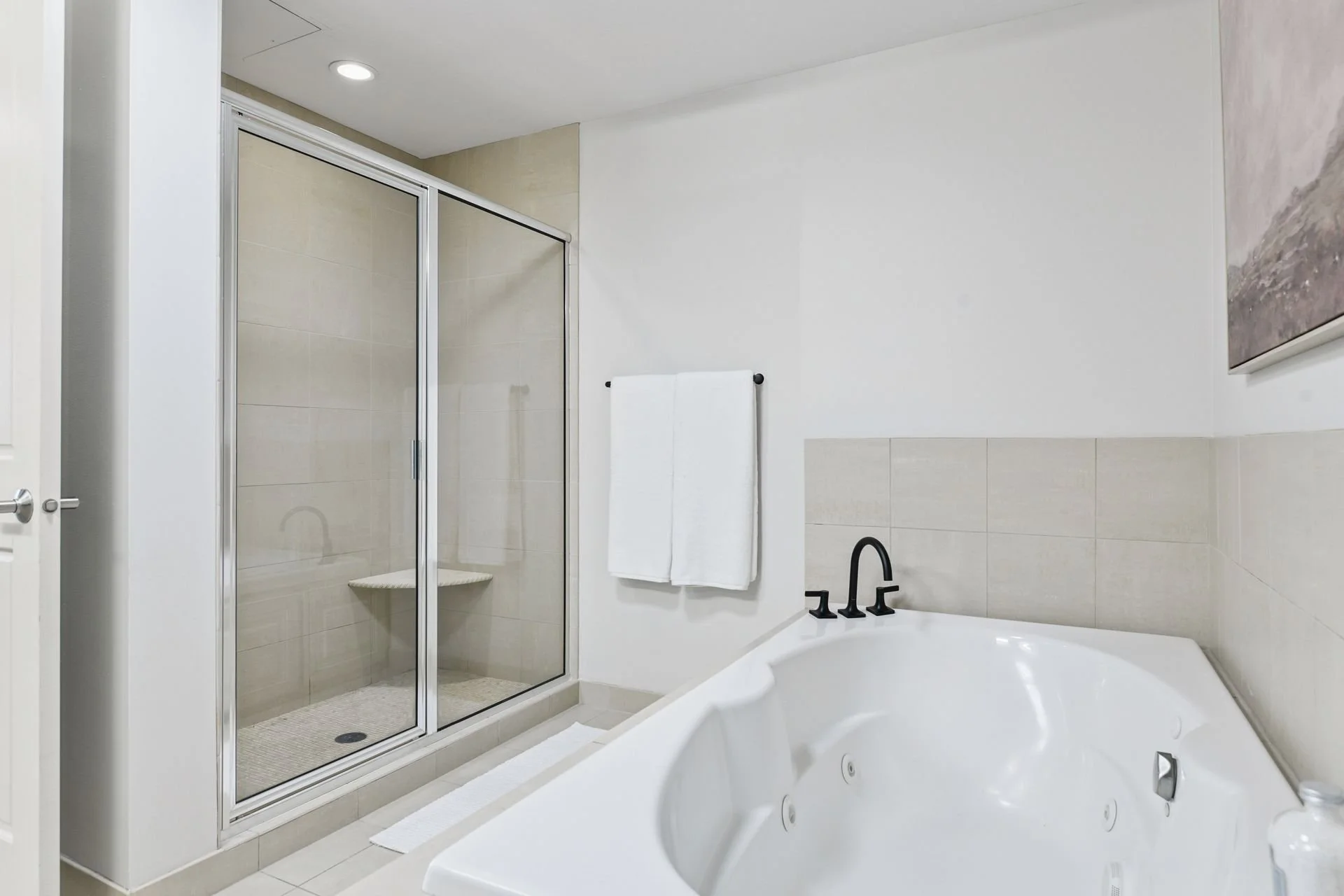 Bathroom with a glass-enclosed shower, a bathtub with black fixtures, and a black towel rack.