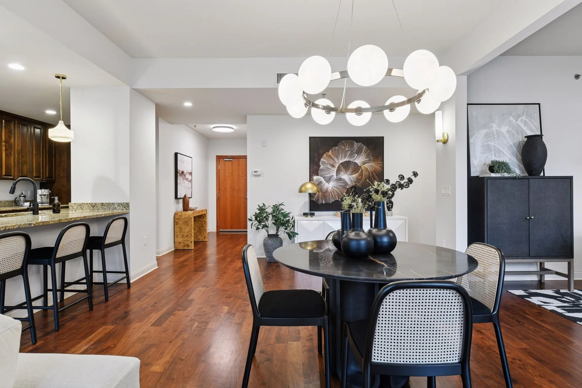 Modern living and dining room with hardwood floors and a large chandelier with white globes.